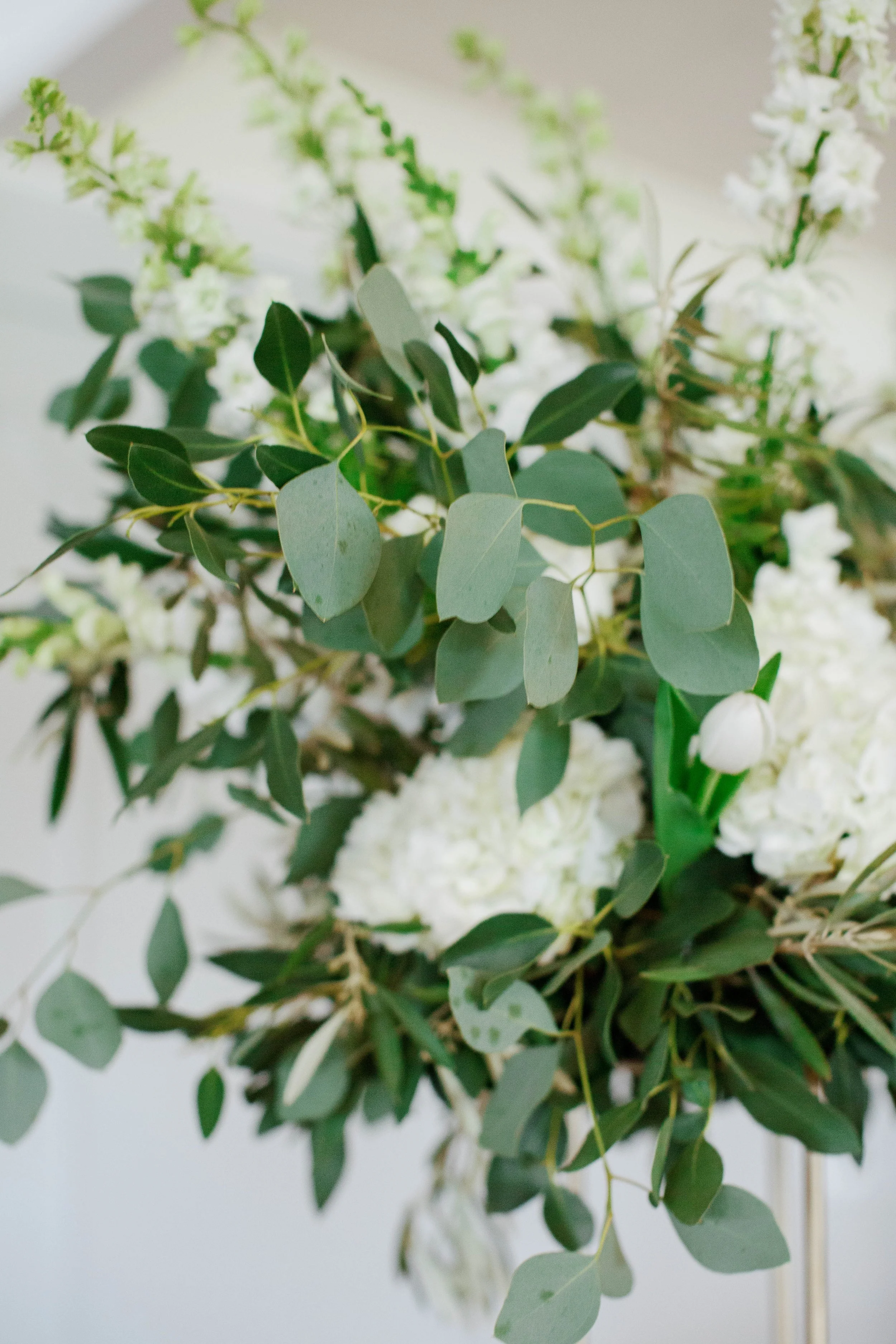 Close-up of a floral arrangement with white flowers and green eucalyptus leaves.