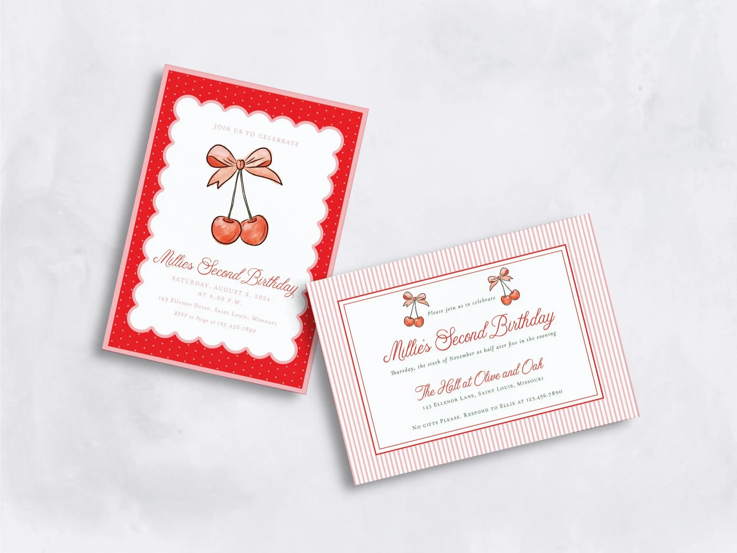 Close-up of red and pink birthday party invitations with illustrations of cherries and bows, placed on a white surface.