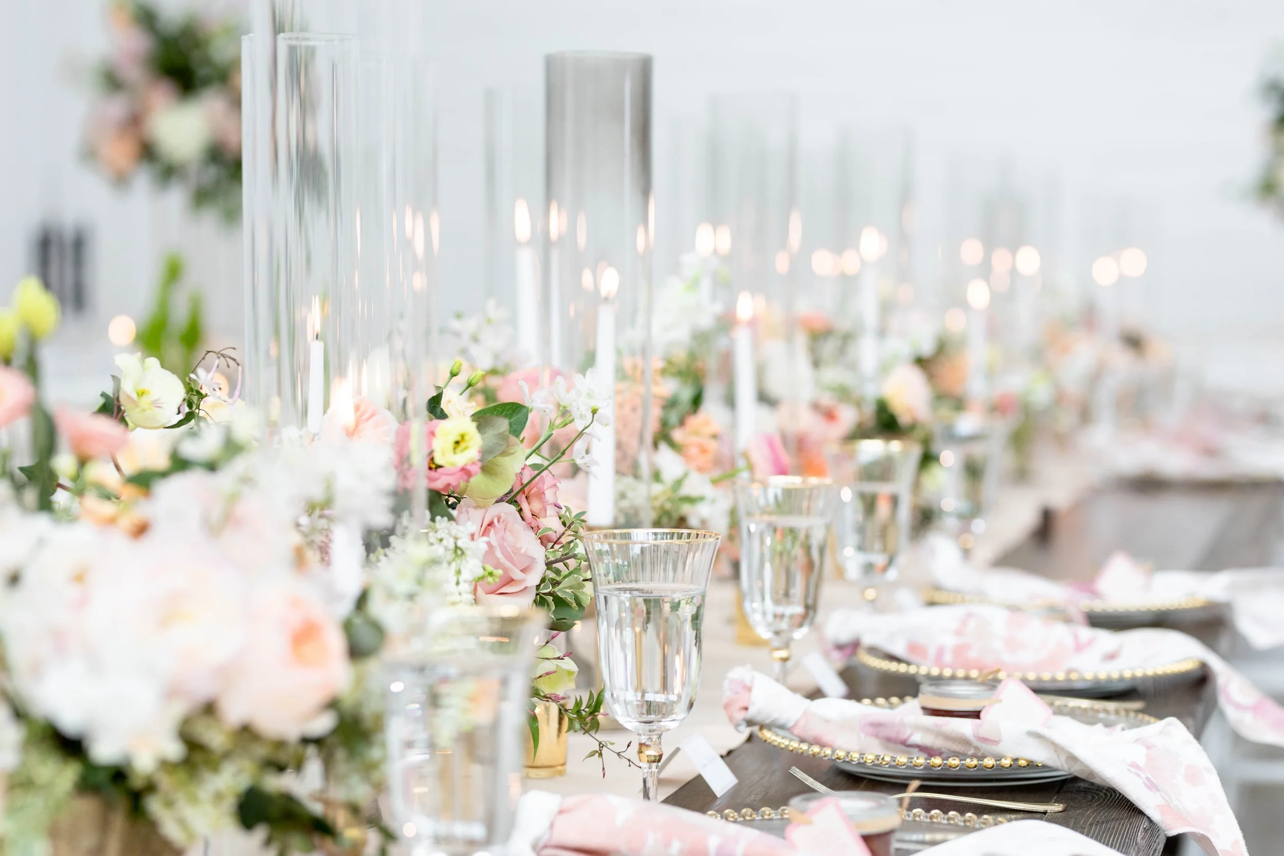 A decorated table with flowers, glassware, plates, and napkins, set for a celebration or event in a bright, elegant setting.