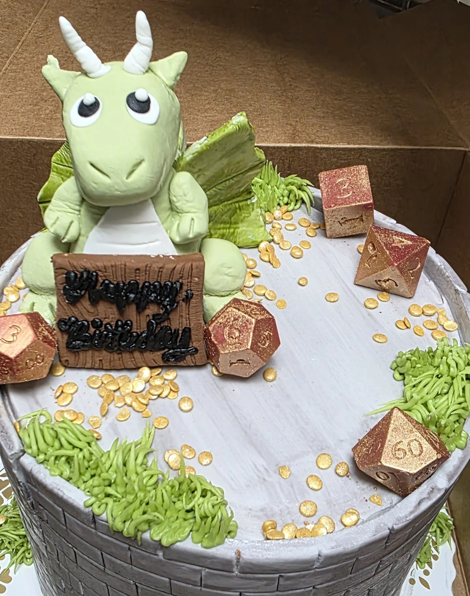 A green dragon beside a textured castle cake made by Jess.