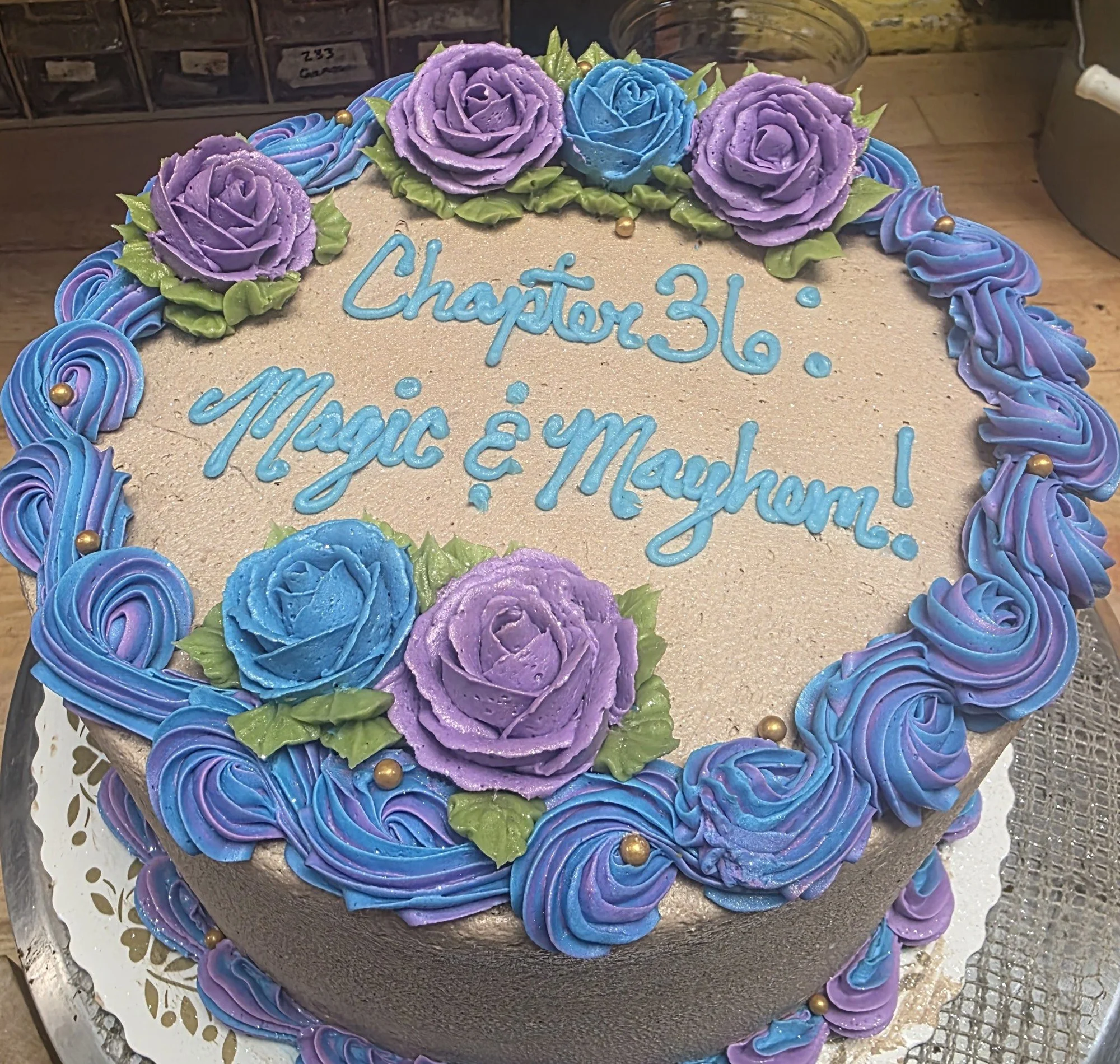 Blue and lavender roses and piped swirls on Jess’s Magic and Mayhem birthday cake.
