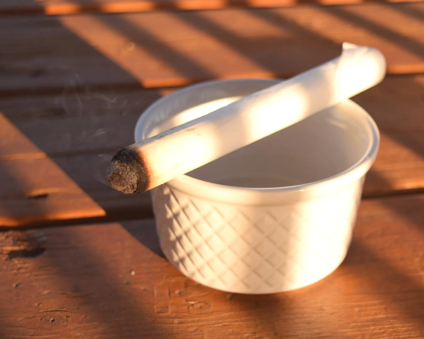 A moxibustion stick is placed on a white ramekin.