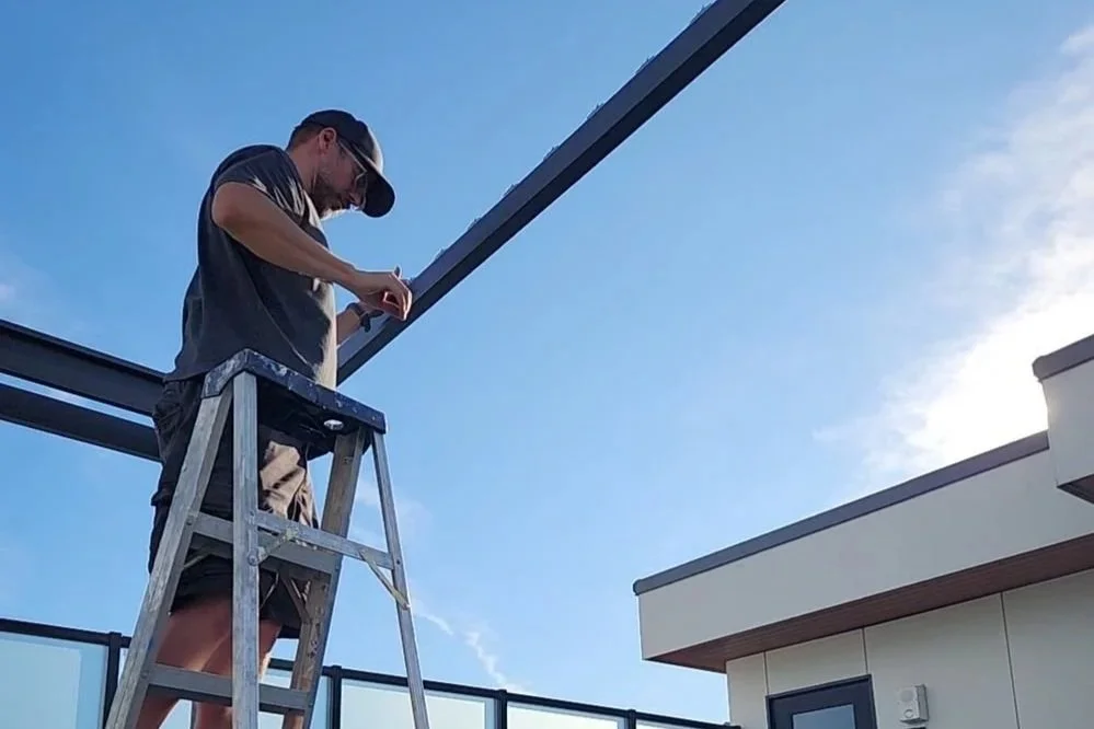 Matt on a ladder installing equipment on a rooftop
