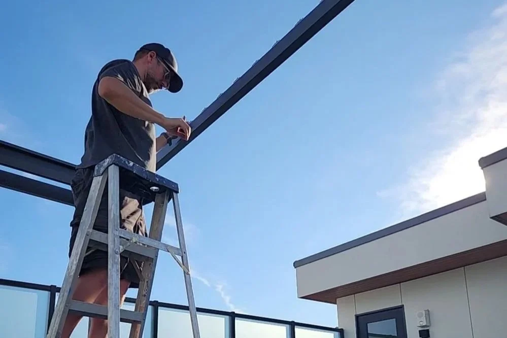 Matt on a ladder installing equipment on a rooftop