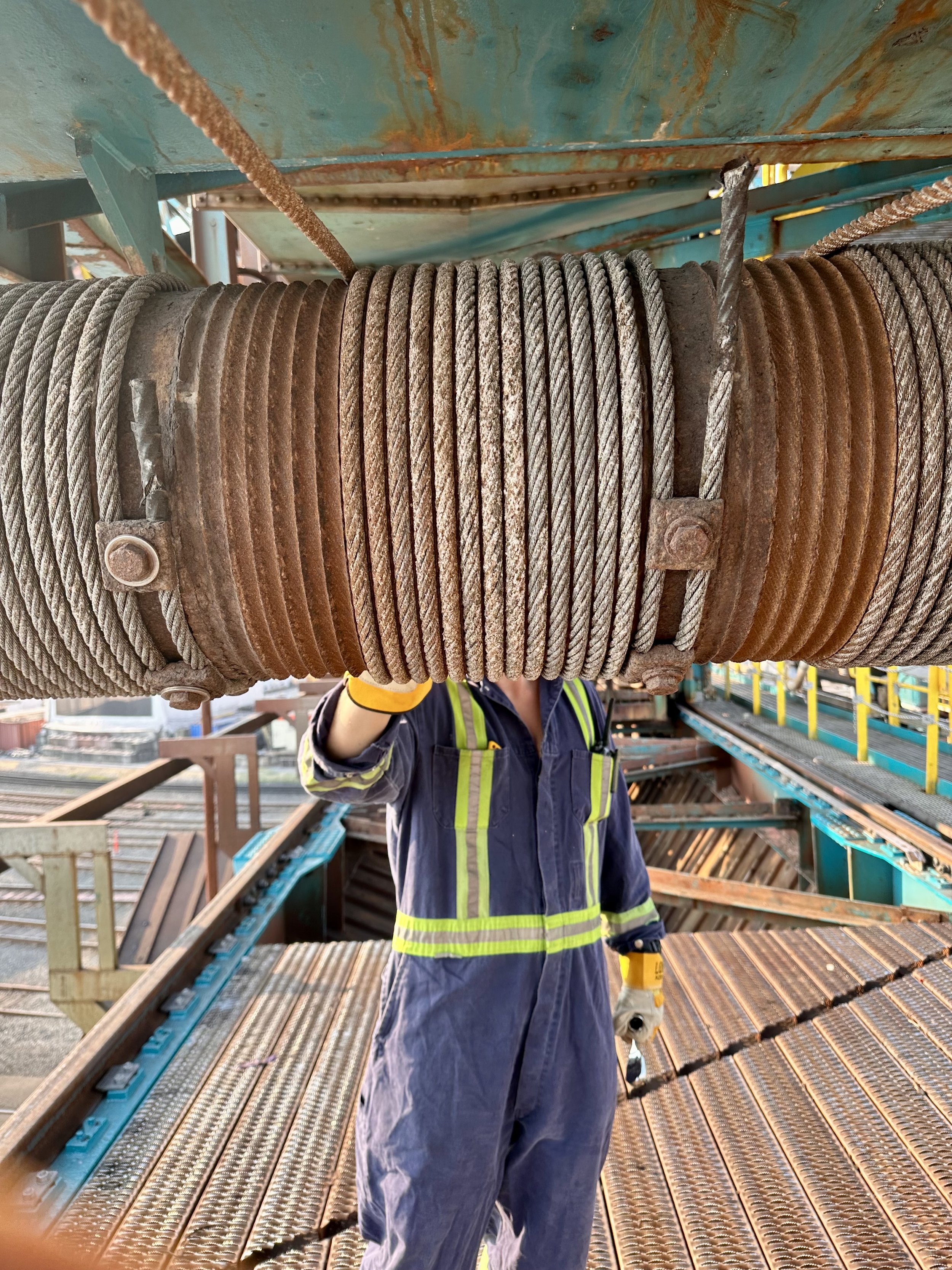 Person wearing safety gear inspecting a large industrial cable coil on a construction site.
