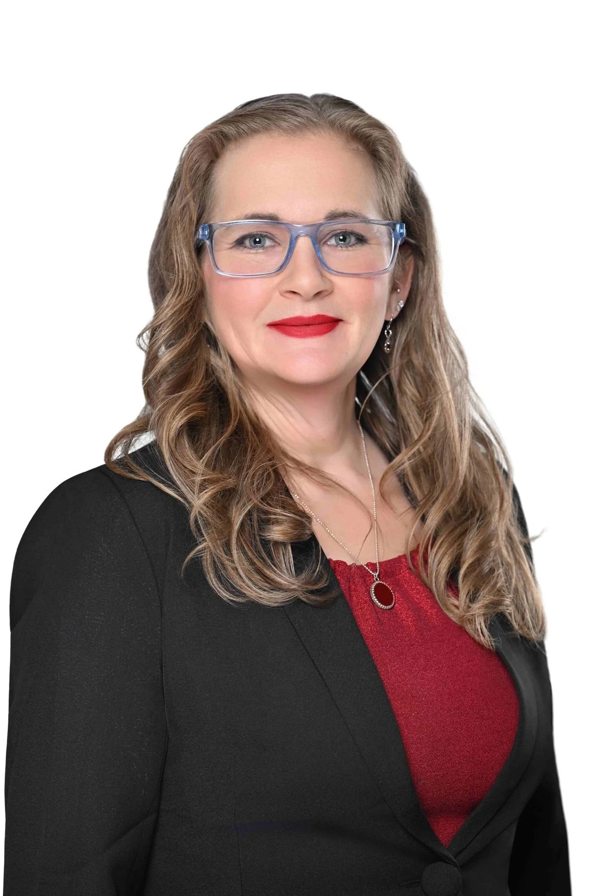 Professional woman with wavy hair, wearing glasses, red lipstick, a black blazer, and a red top, smiling against a white background.