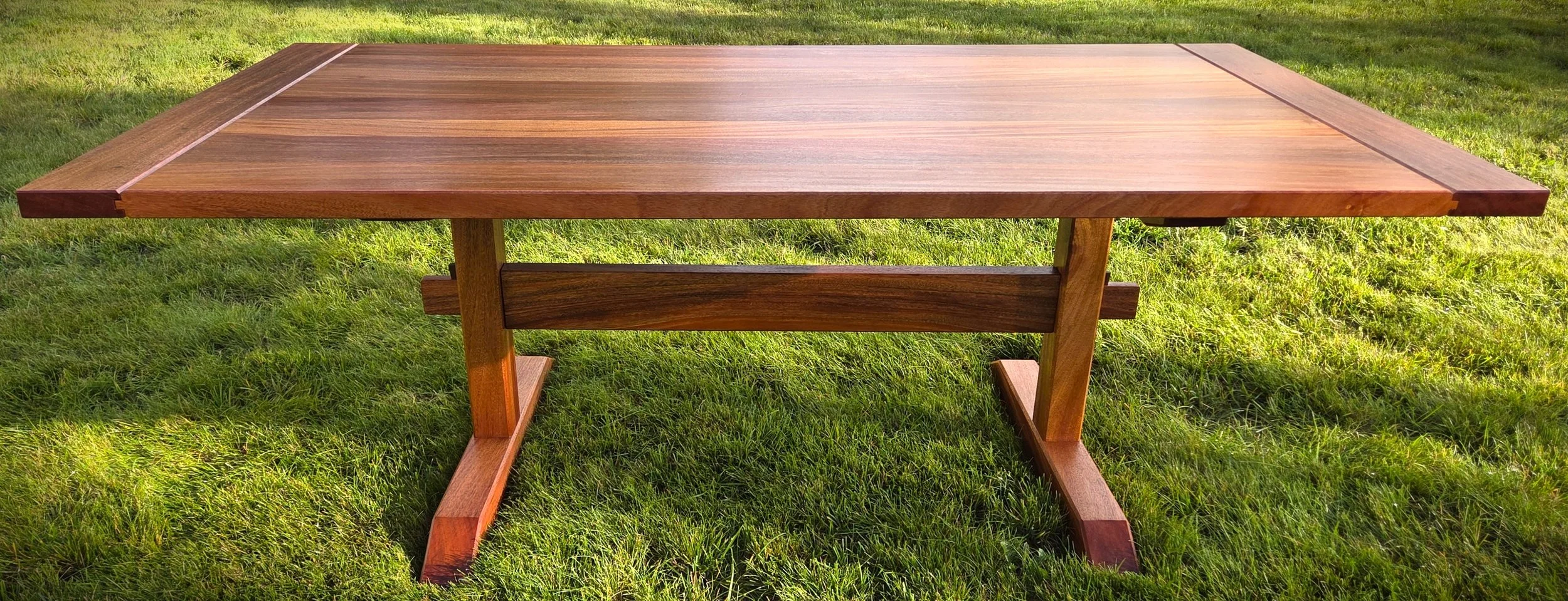 Handcrafted wooden picnic table with bench seating on a grassy lawn