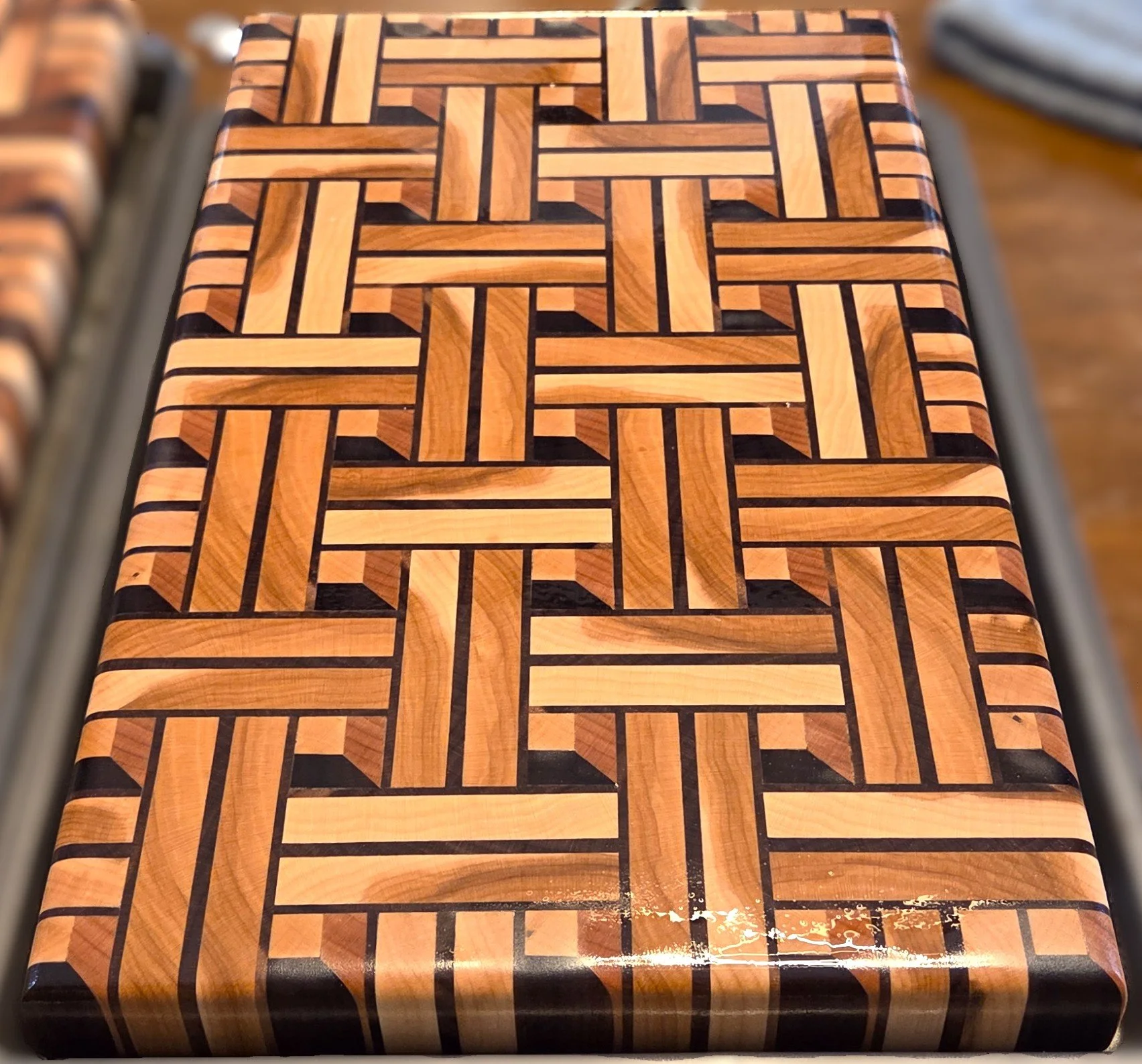 Close-up of a handcrafted wooden tabletop featuring an intricate geometric parquet pattern in contrasting light and dark wood.