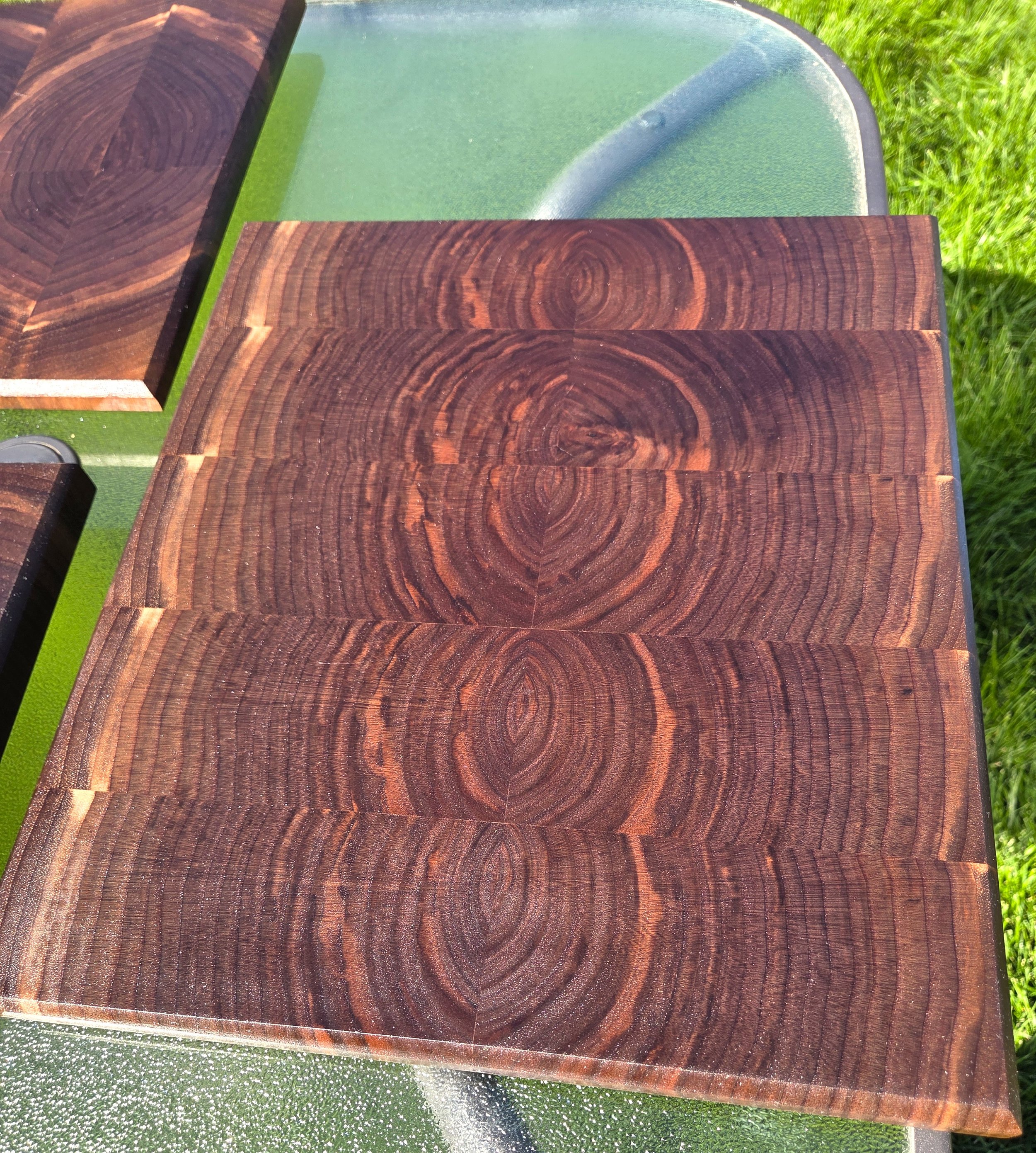 Close-up of dark wooden panels with prominent circular grain patterns on a green outdoor surface.