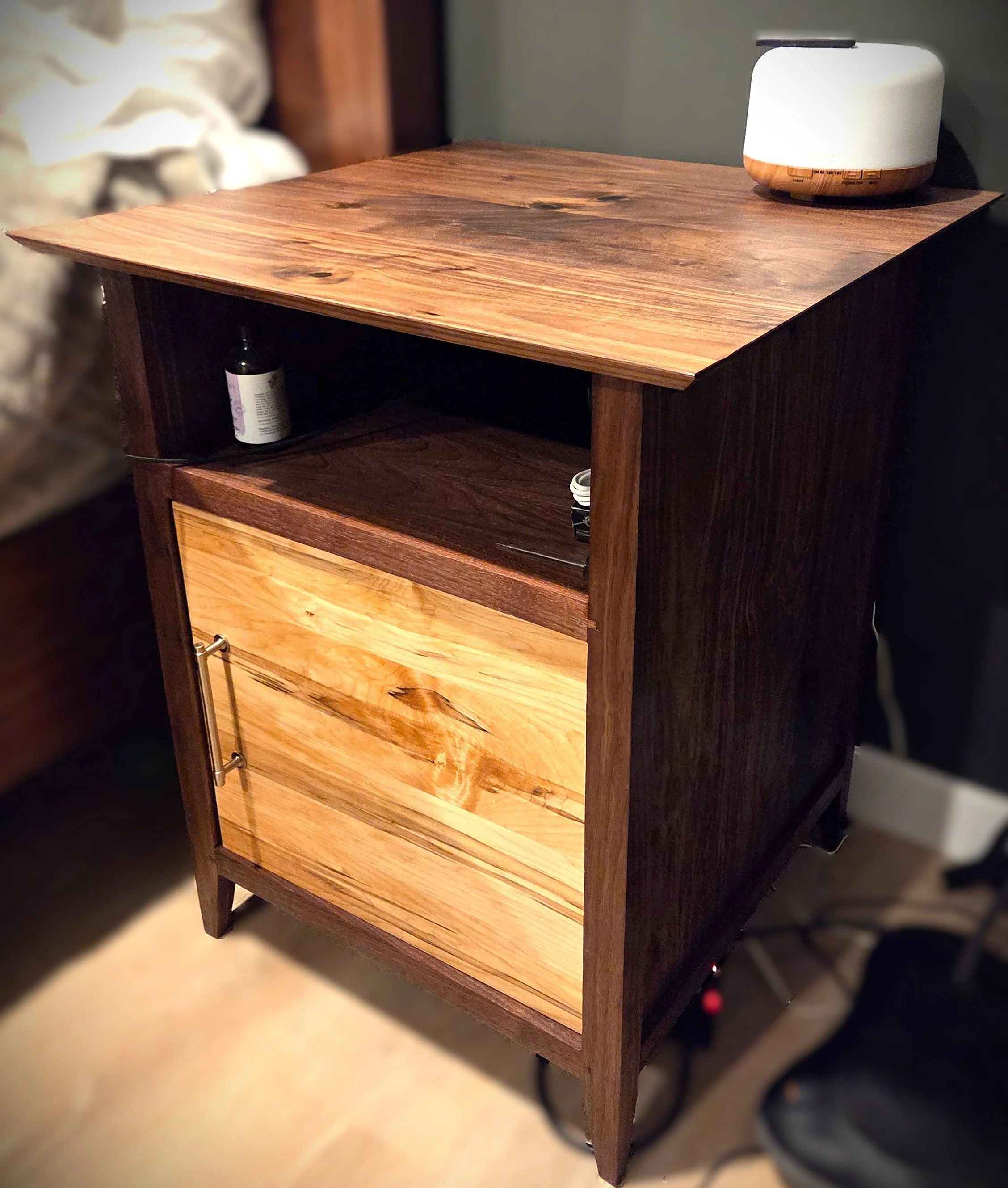 Rustic wooden side cabinet with drawers and open shelving, topped with a white diffuser.