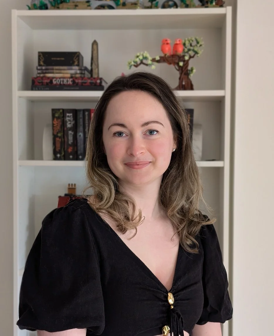 An image of a woman standing in front of a bookcase