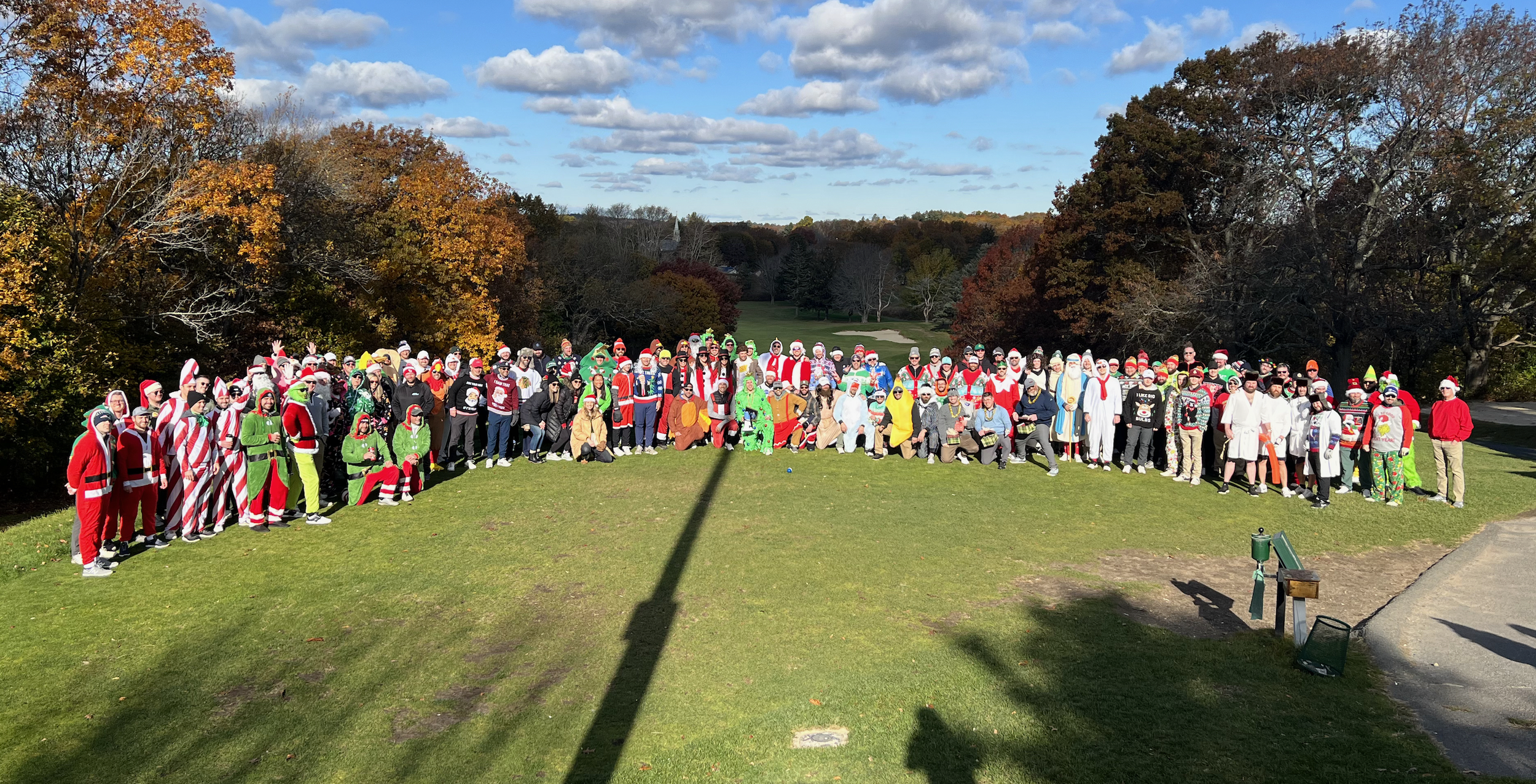 Large group in festive Christmas costumes posing on a golf course in autumn