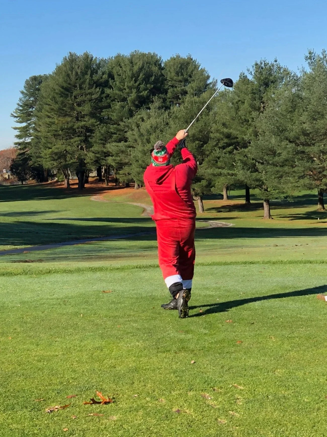 Golfer in a red outfit swinging a golf club on a sunny course