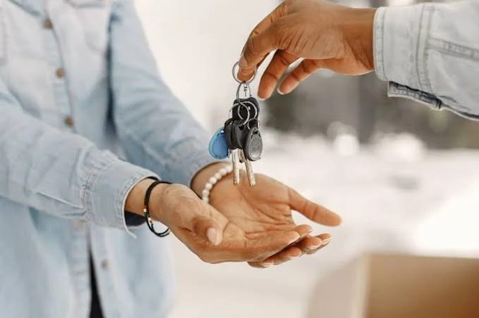 Person handing over keys to another person.