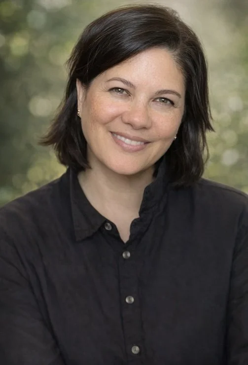 portrait of Kelly Newsom, who is wearing a black shirt, with a green shimmering background