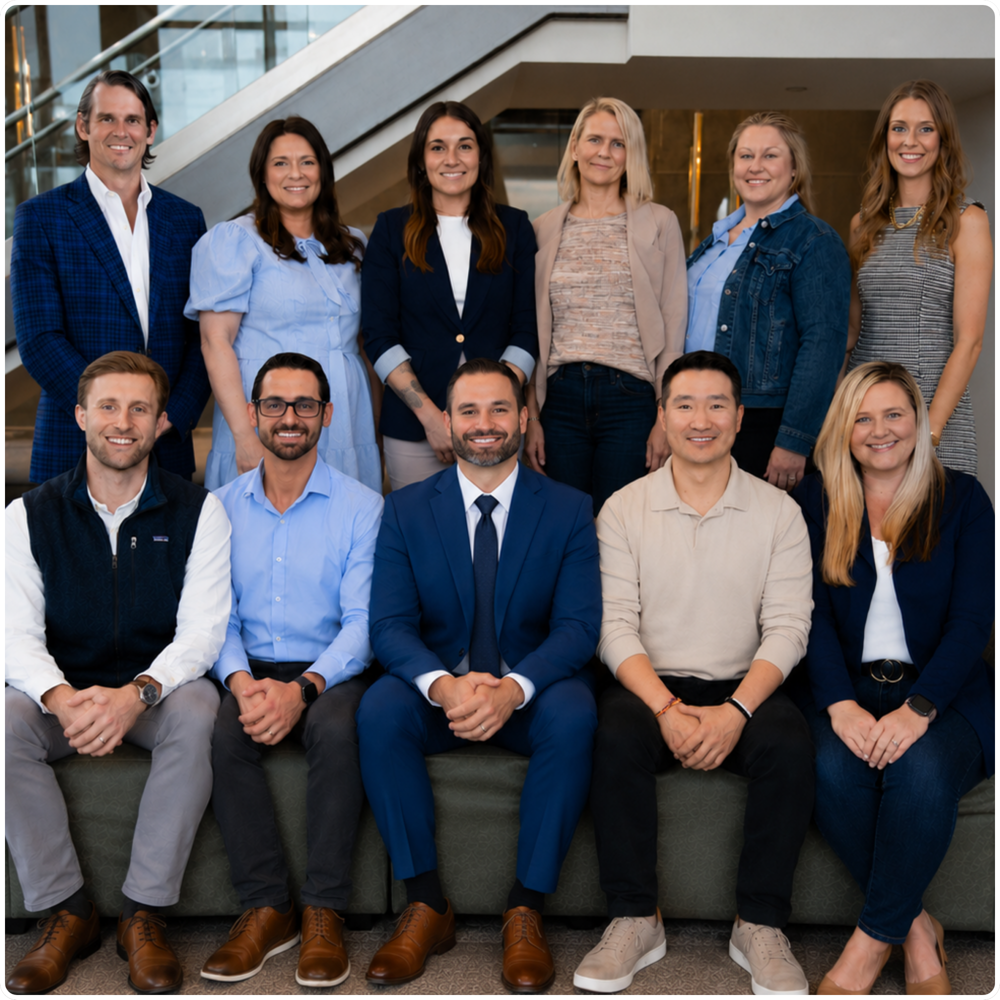 Group portrait of 11 diverse business professionals posing in two rows inside a modern office