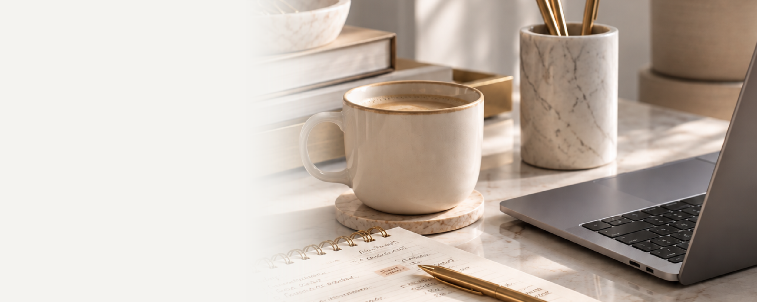 Cozy workspace with coffee mug, open planner, gold pen, books, marble pencil holder, and laptop.
