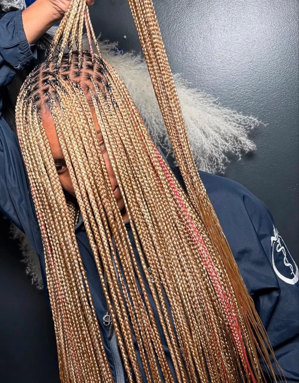 Personne portant de longues tresses africaines blondes avec des mèches roses
