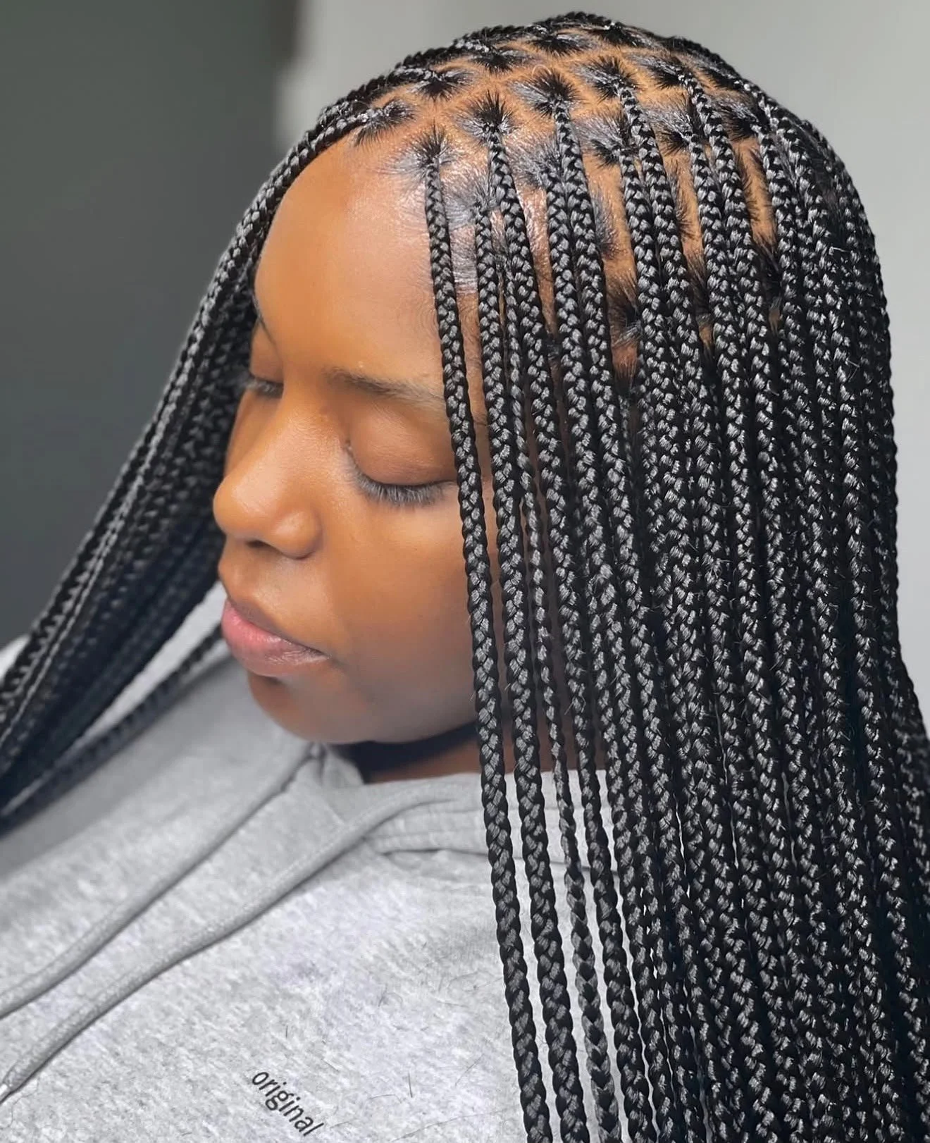 Portrait de profil d’une femme noire portant de longues tresses africaines noires, avec raies géométriques et motif en épi.