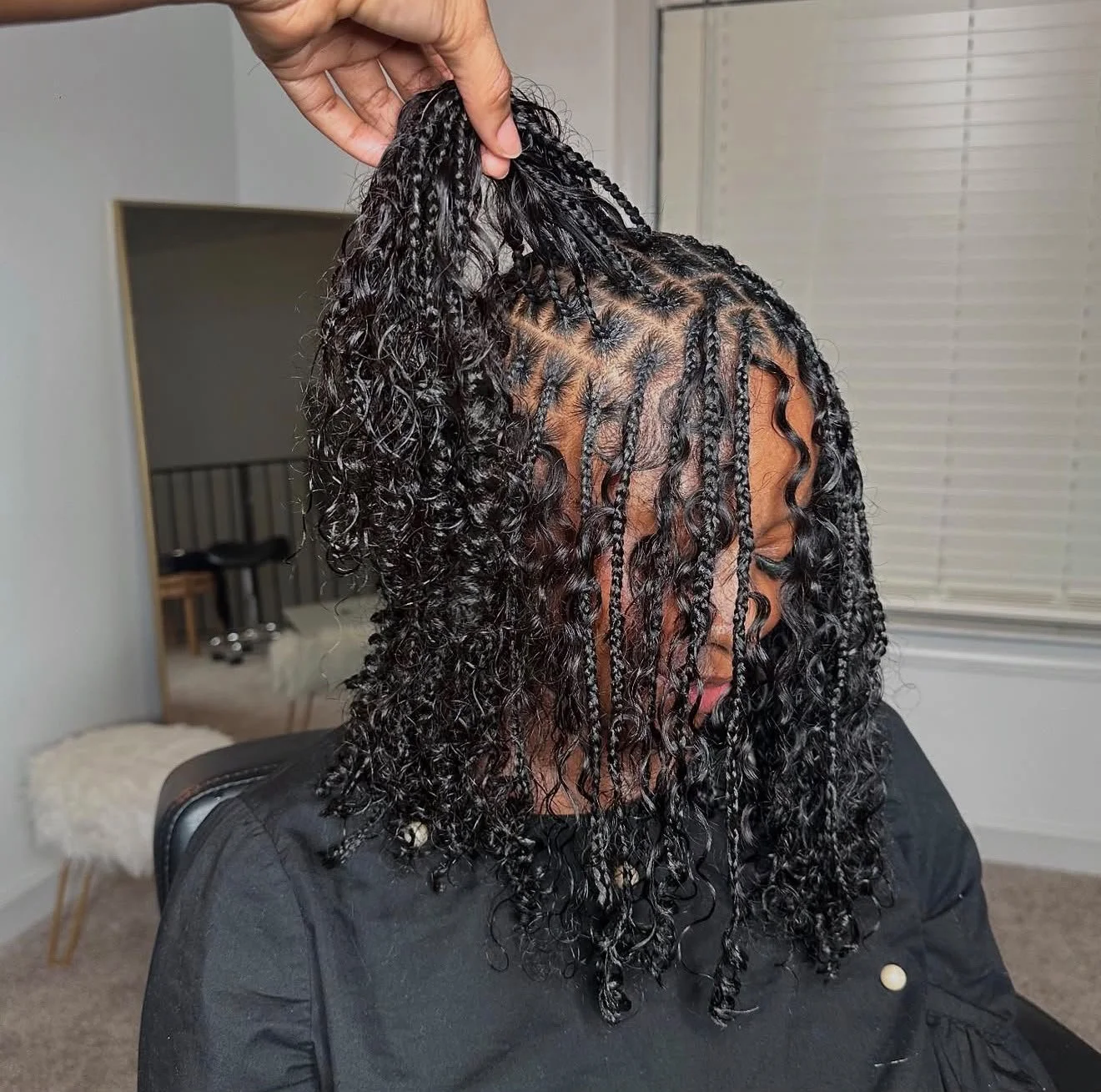 Coiffure protectrice avec tresses fines et boucles naturelles sur cheveux noirs texturés.