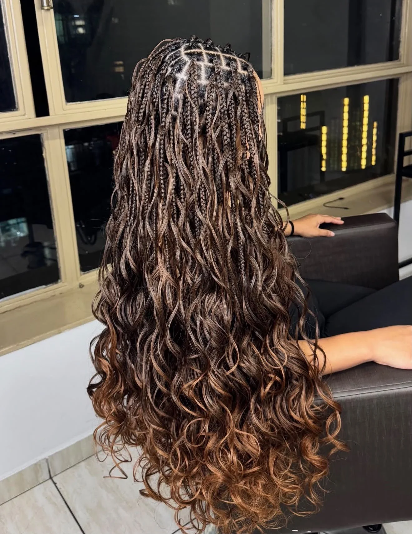 Vue arrière d’une coiffure avec tresses fines et longues boucles ondulées brun cuivré.