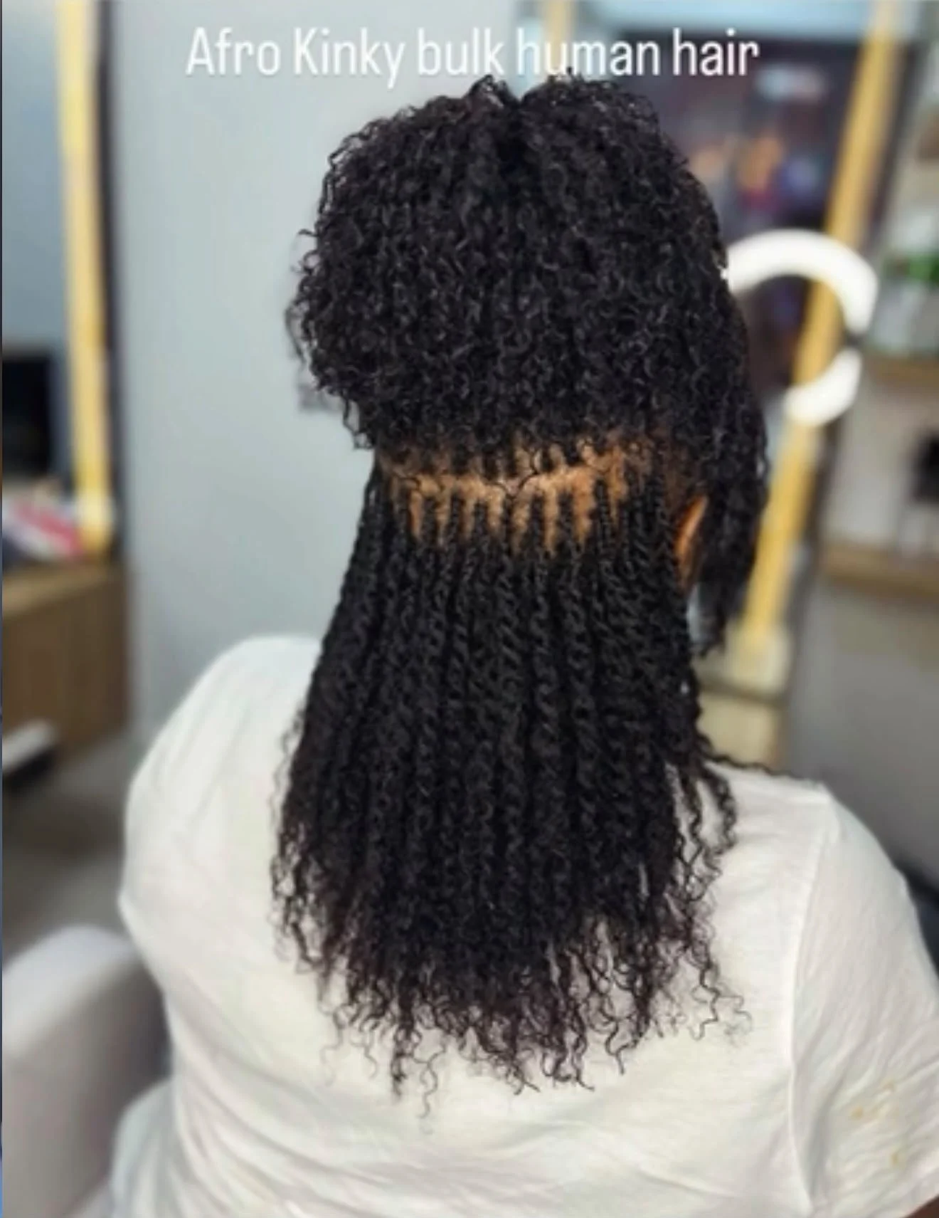 Vue arrière d’une coiffure en cheveux humains afro crépus, avec boucles serrées et extensions longues.