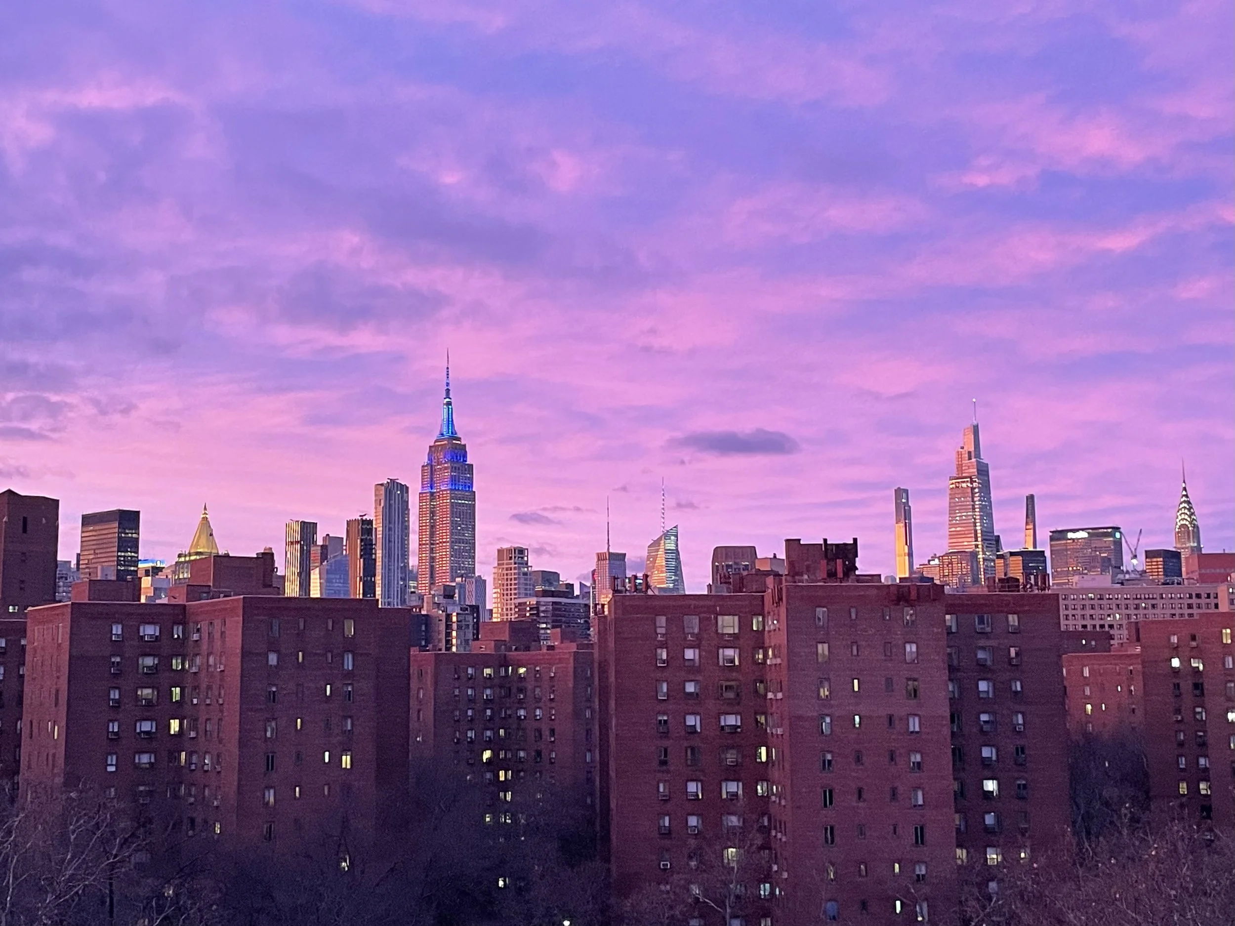 Pink sunset of new york city with the empire state building in sight.