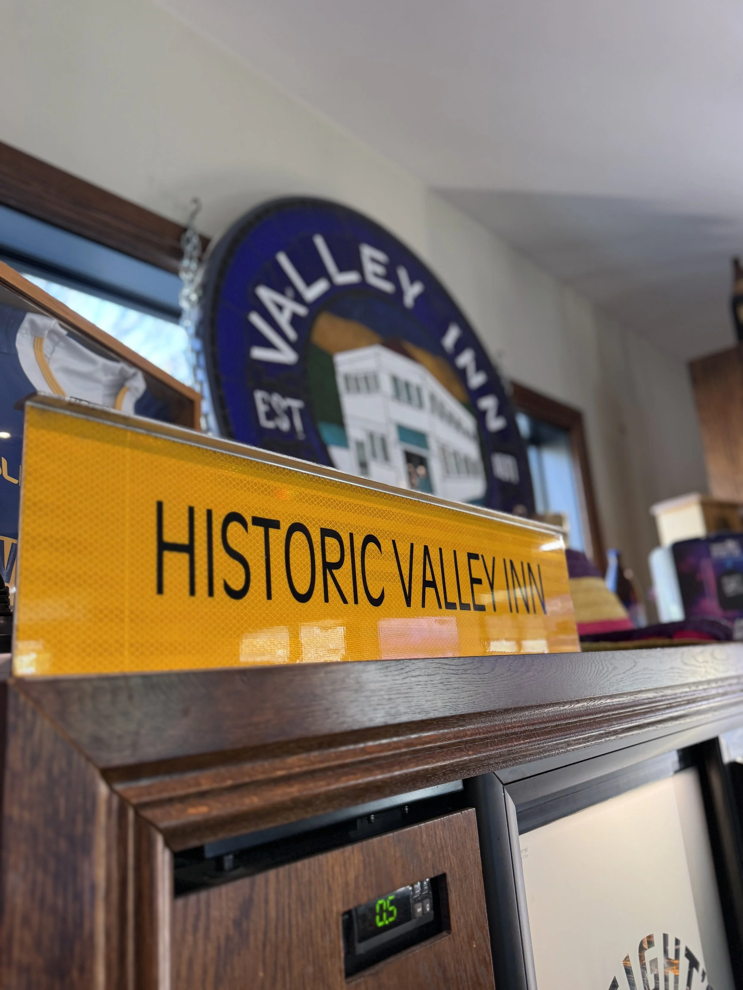 Close-up of a yellow reflective “Historic Pullman” sign displayed on a wooden cabinet, with a Chicago neighborhood map and blue clock in the background.