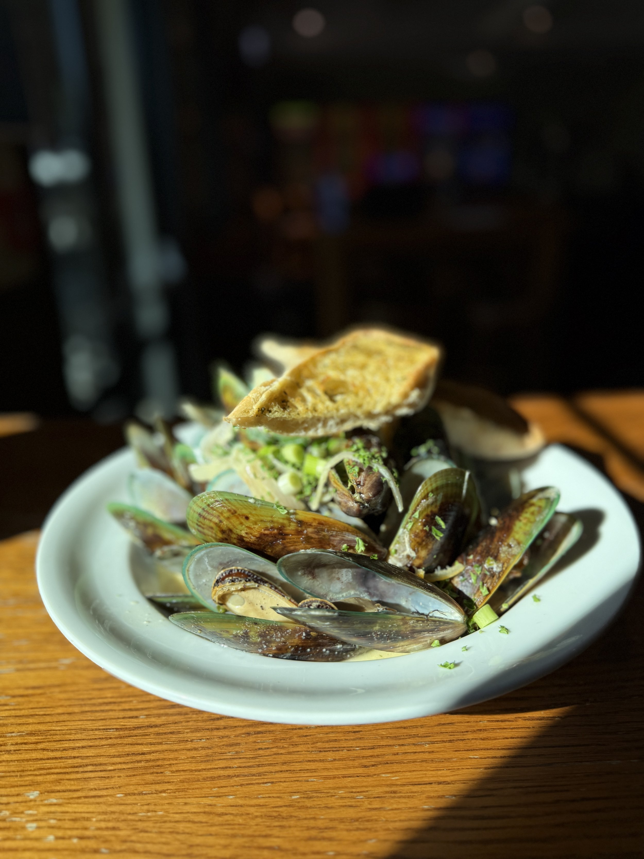 Steamed mussels and clams garnished with herbs and served with toasted bread on a white plate