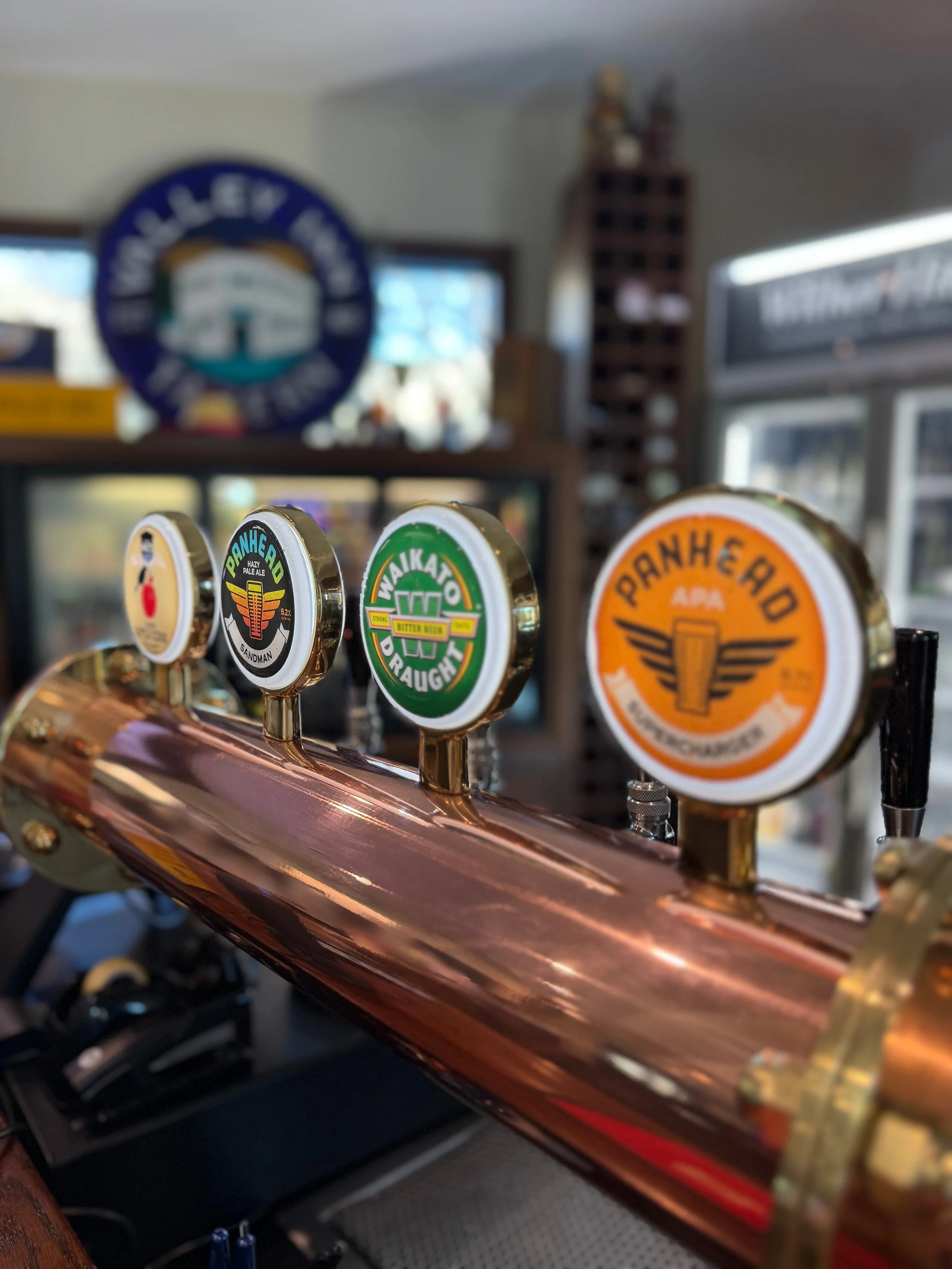 Close-up of assorted craft beer taps at a pub bar, including Pranhead, Wainwright, and Punk IPA handles.
