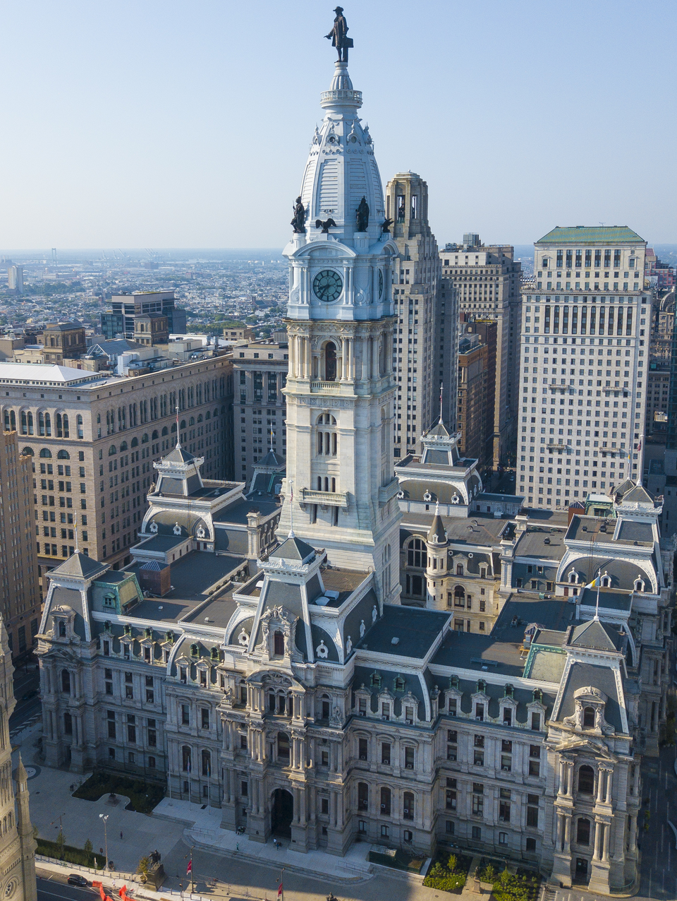 Aerial view of Philadelphia City Hall, featuring its ornate clock tower and William Penn statue, surrounded by downtown buildings.