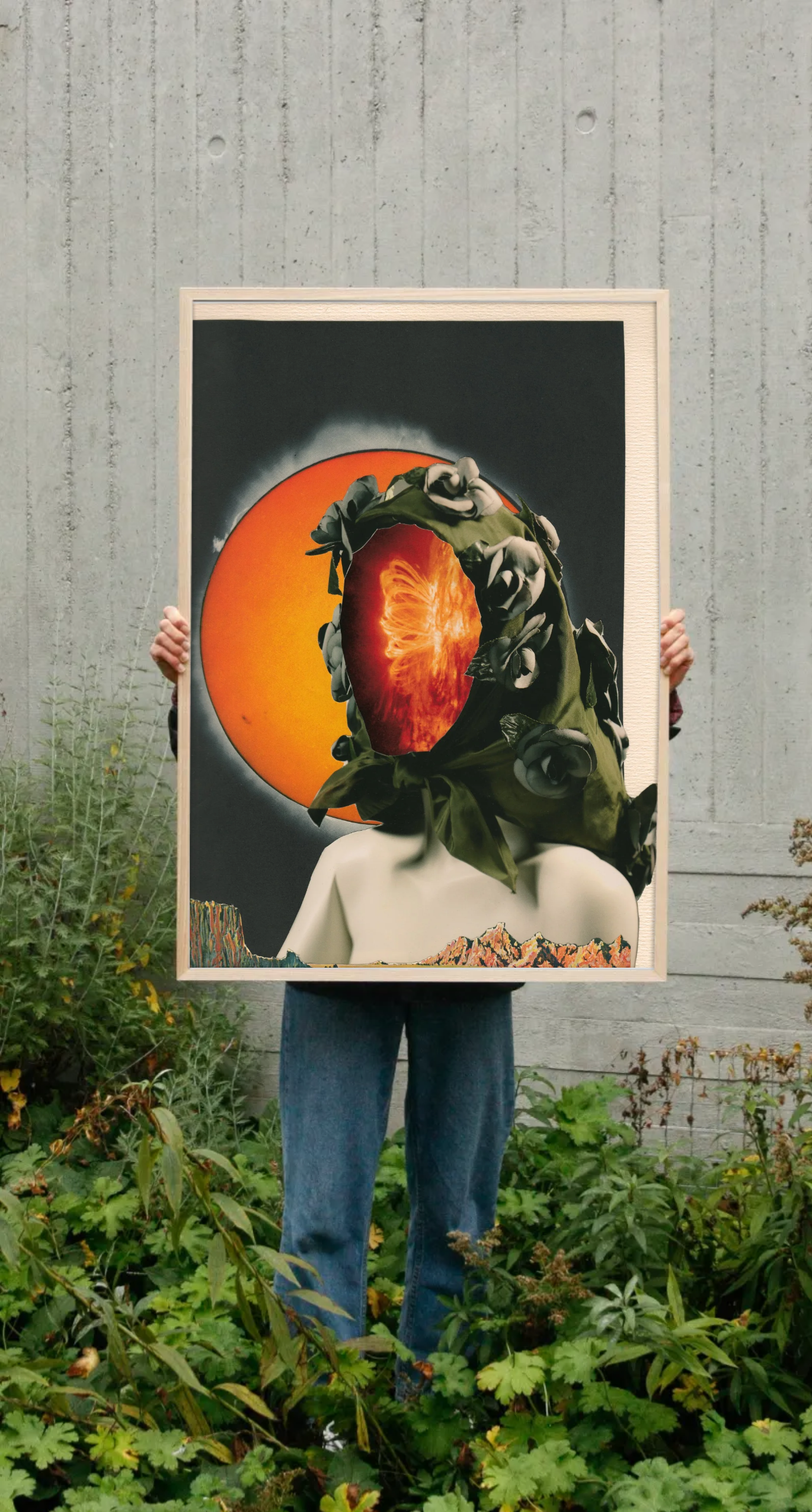 a person in a garden holding up a collage by Amanda Clifford, the collage features the shape of a woman in a headscarf with the fire of 100 burning suns as a face, in front of an inversed solar eclipse from the sun's perspective