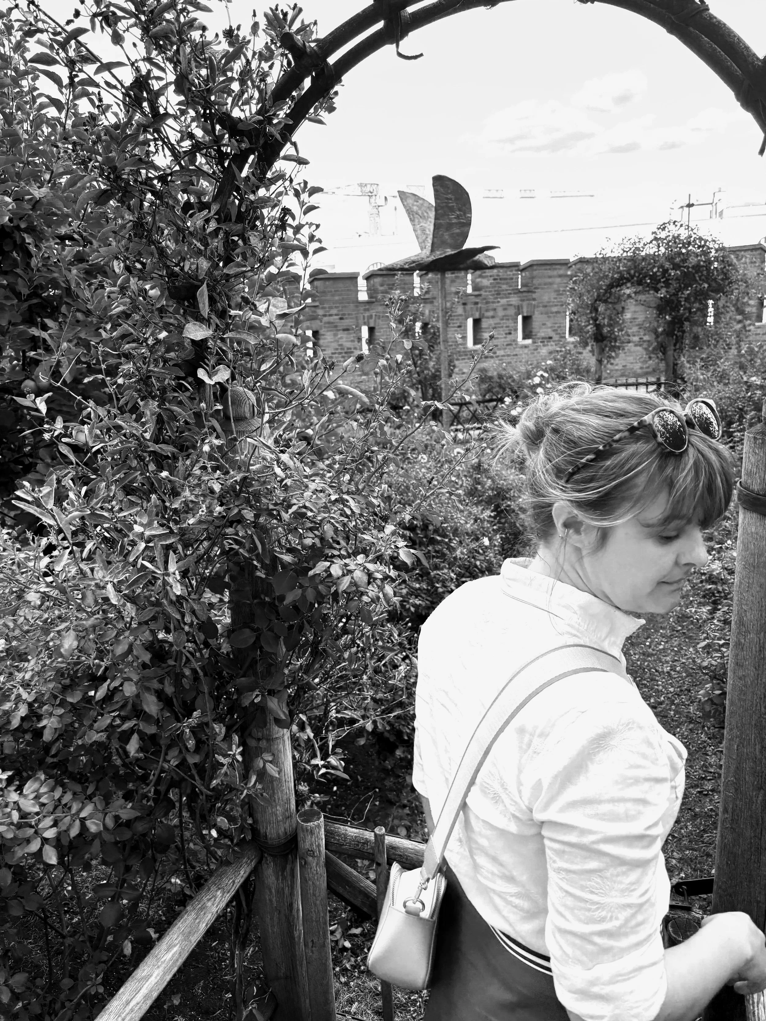 A black and white photo of Amanda Clifford admiring the gardens in Wawel Castle in Krakow Poland