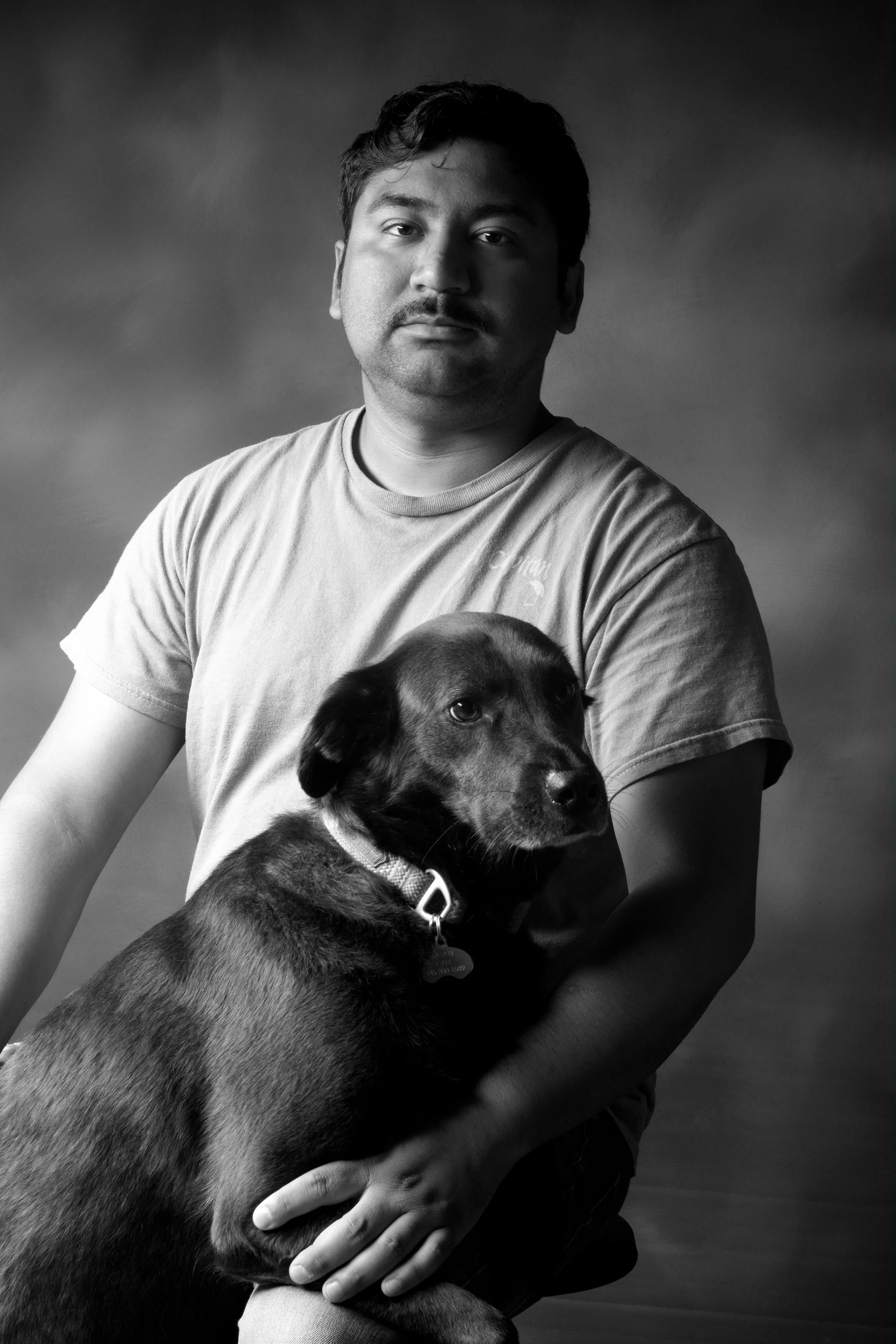 latin man with black dog on lap