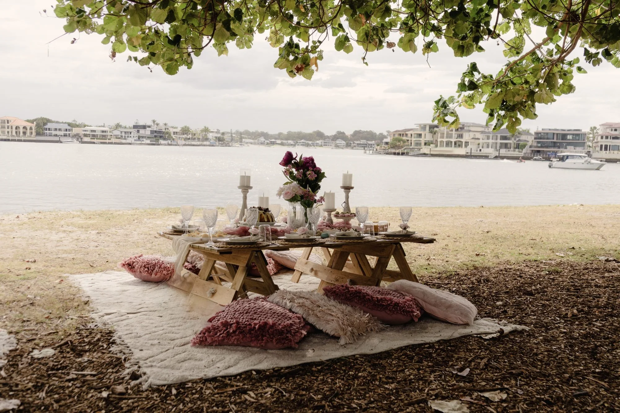 Lakeside picnic setup with pink cushions and rugs, Gold Coast