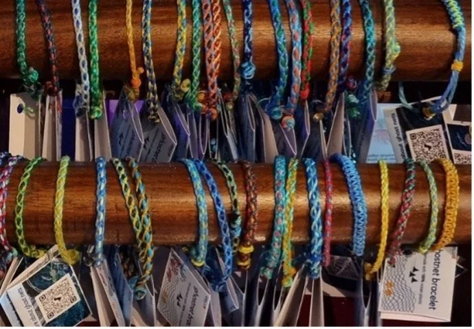 Colorful woven friendship bracelets hanging on a wooden display.