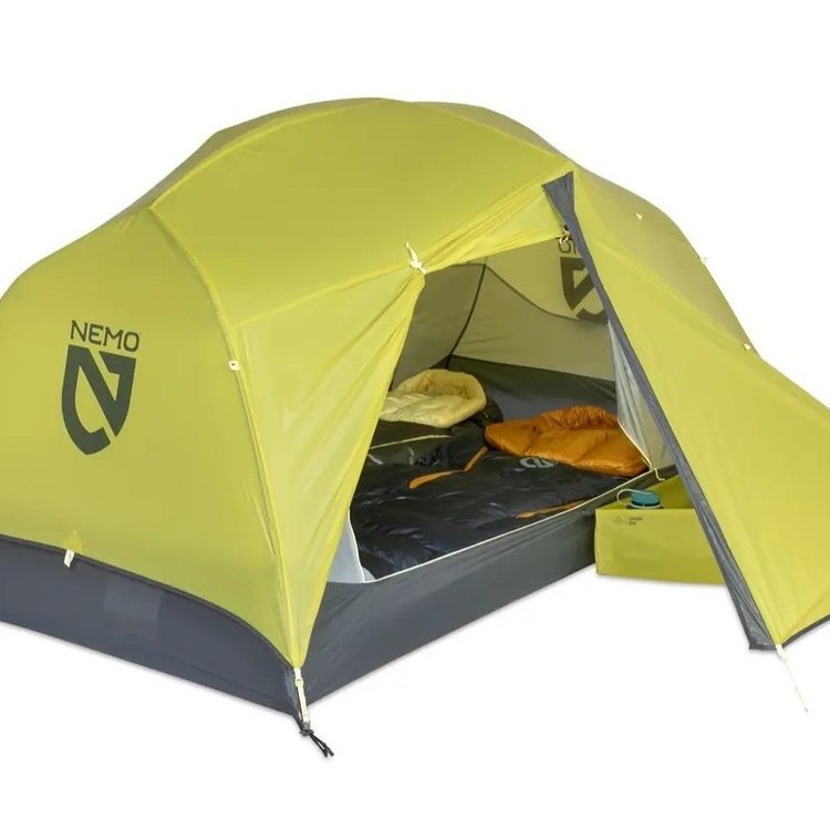 A green Nemo tent set up with sleeping bags and a mat inside, suitable for camping.