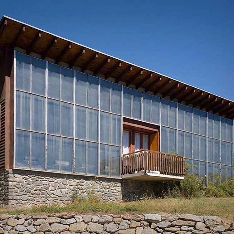 A trombe wall places a glass panel in front of a dark masonry wall. Solar heat passes through the glass, is absorbed by the thermal mass wall, and then slowly released into the building. Direct solar radiation has a shorter wavelength and is easily c