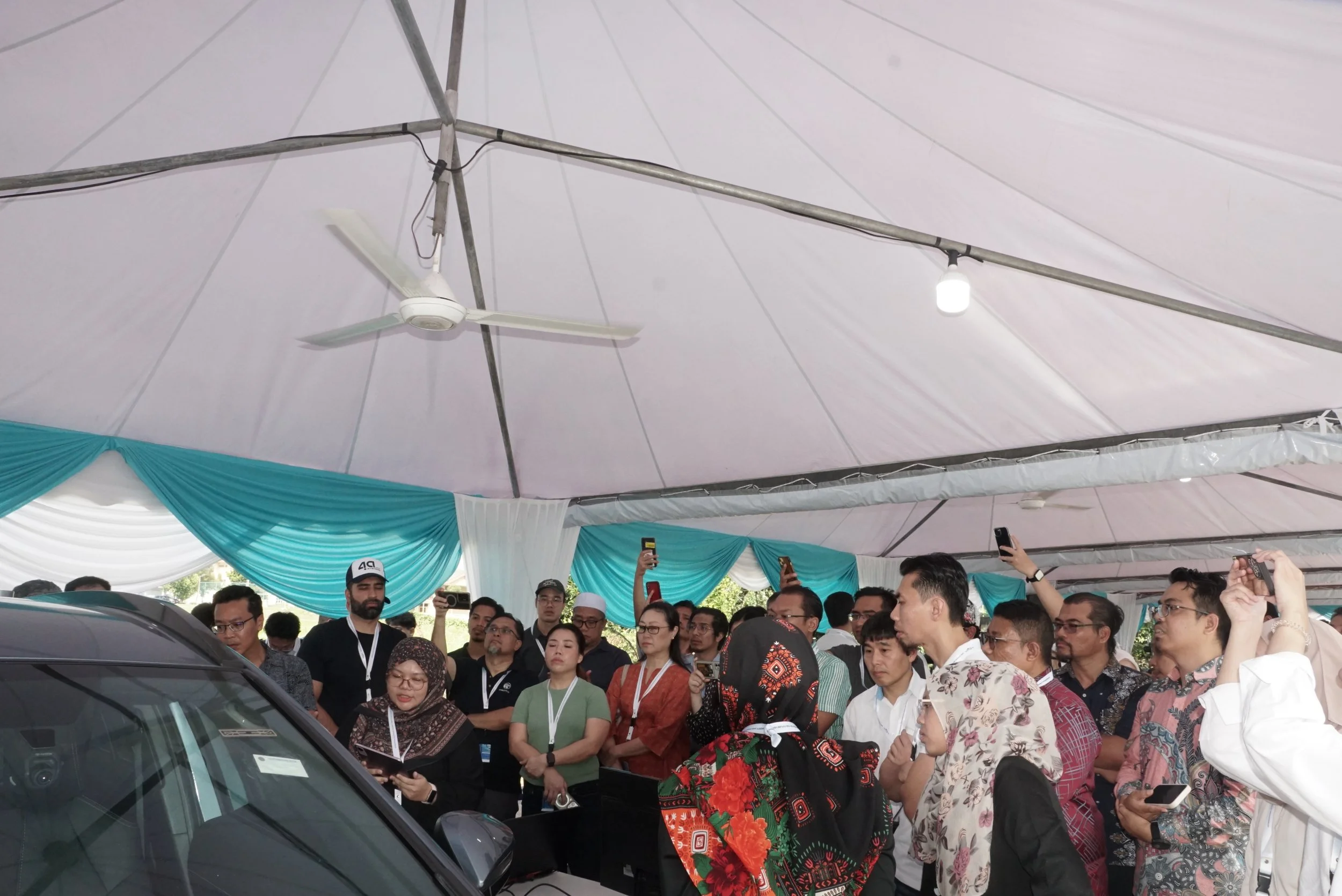 Conference participants gathered around a vehicle during a live demonstration of the kiDS CPD-DS3 Child Presence Detection Dummy at SHIFT 2025, showcasing its application in automotive safety testing.