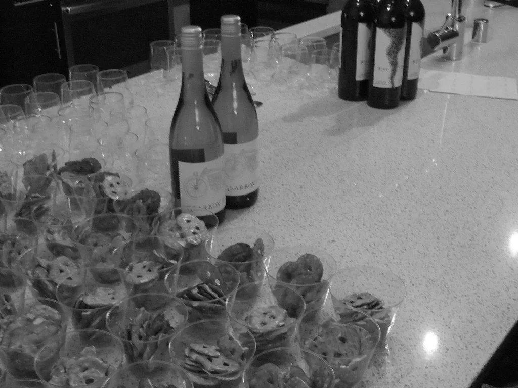 A bar counter with several glasses of wine, bottles of wine, and a plate of cookies.