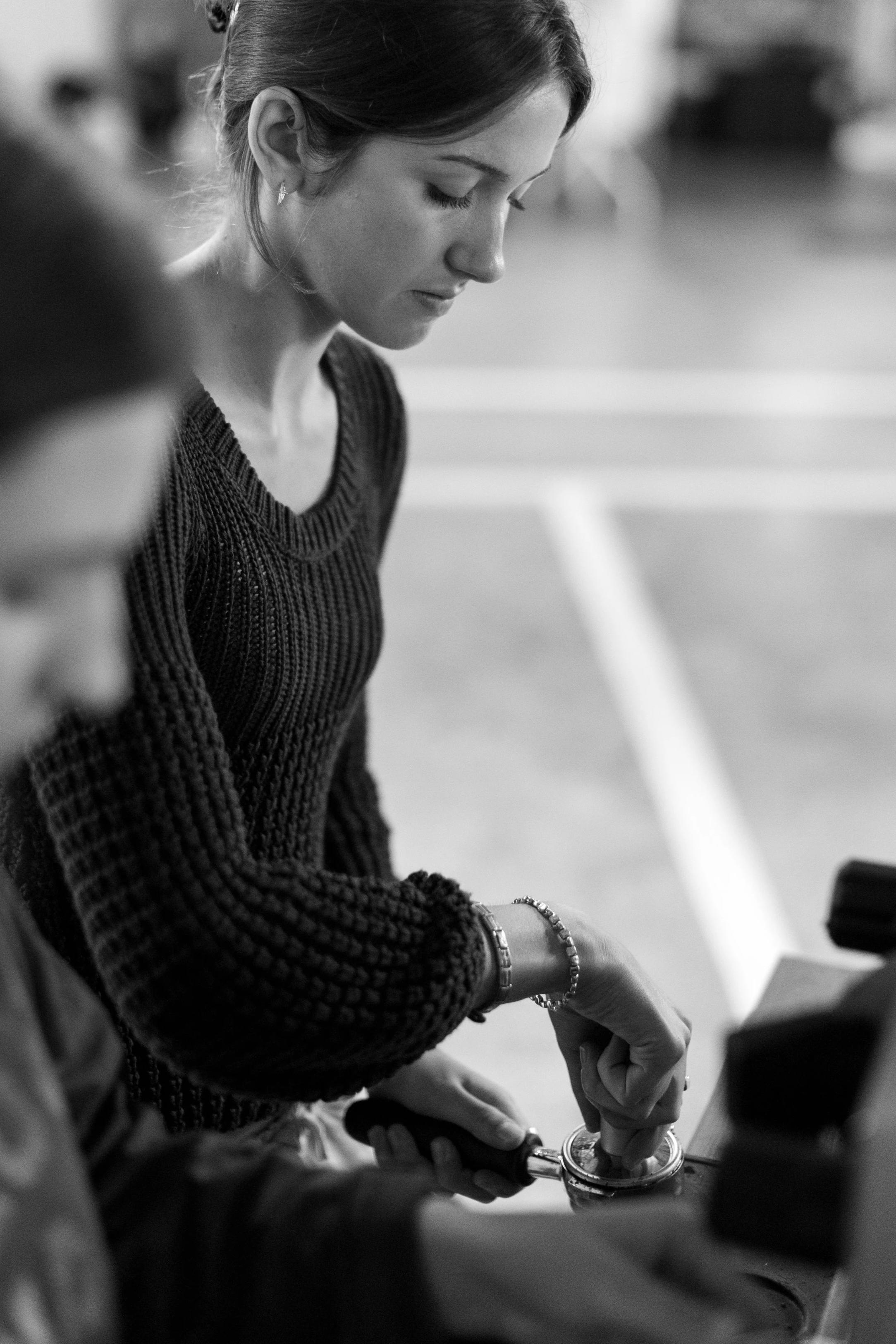 Black and white close up of a barista tamping coffee at the coffee cart