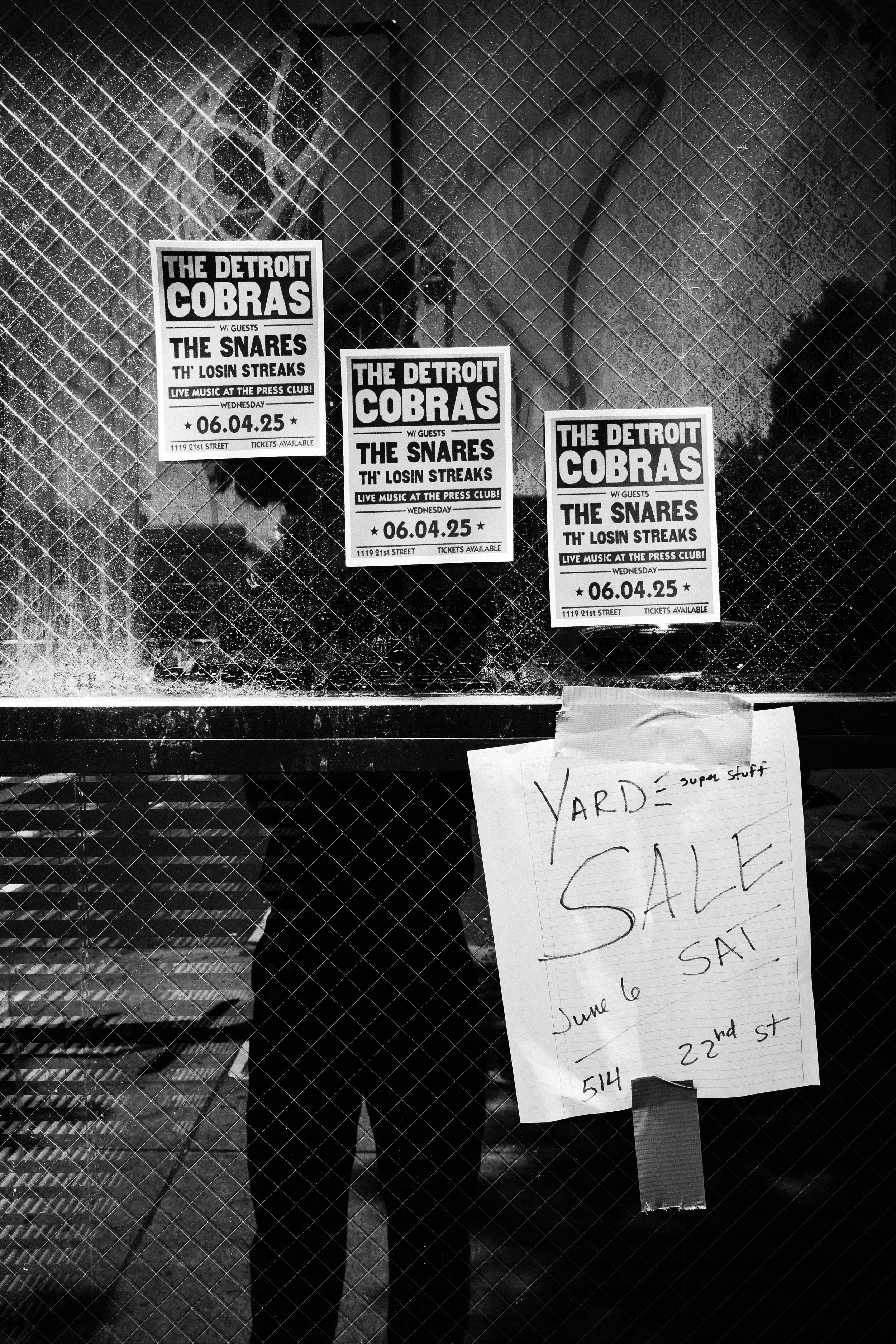 Black and white photo of three posters advertising a live music event featuring The Snares and Th' Losin Streaks at the Press Club on June 4, 2025, on a metal mesh window.