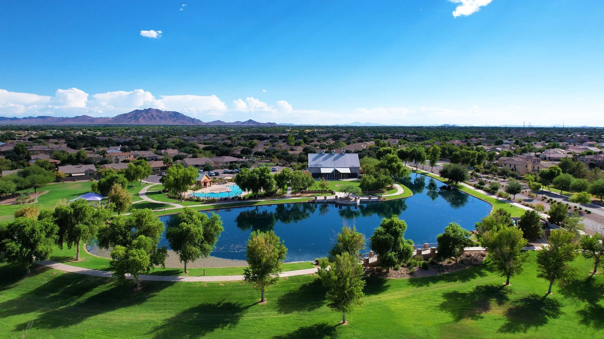 Lake, clubhouse, and community pool with mountain views at Power Ranch in Gilbert, Arizona