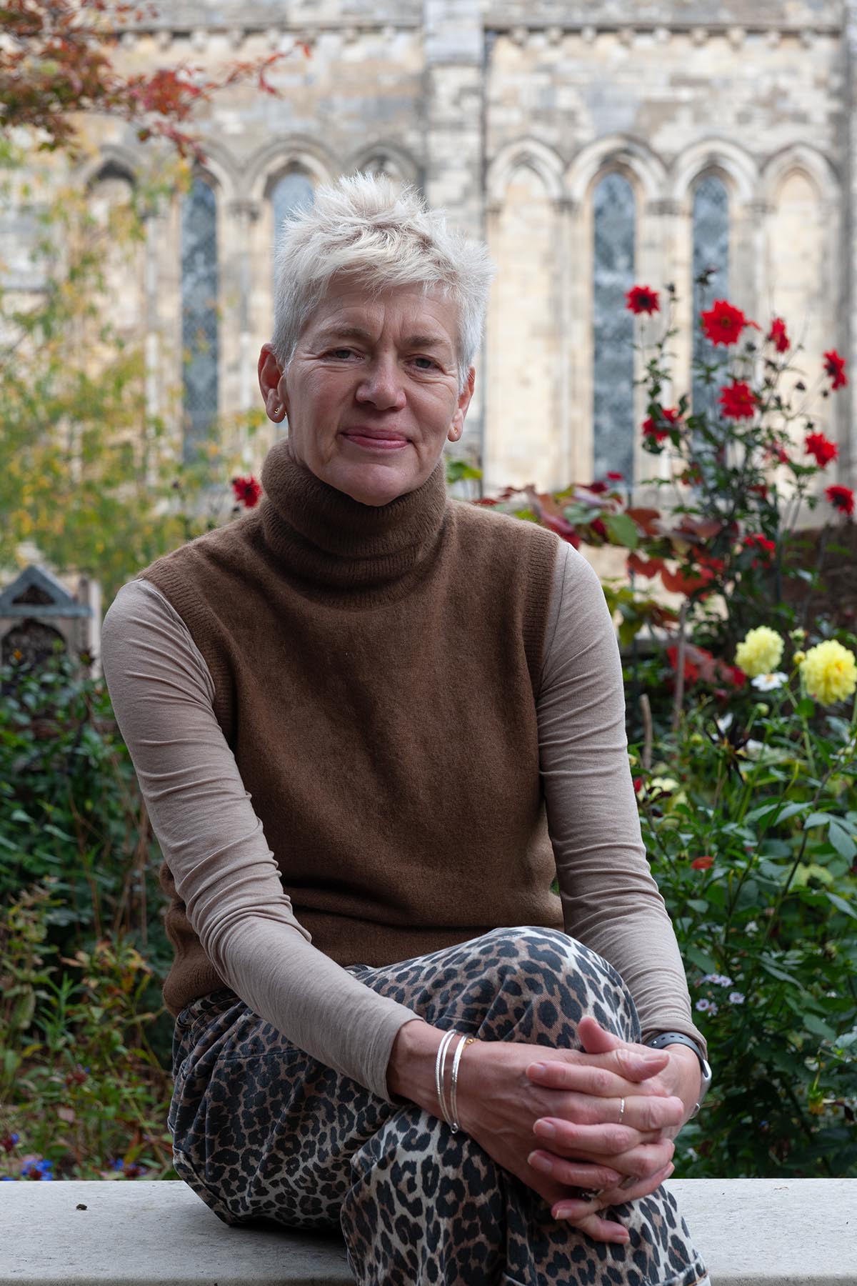 Dr Michelle Lowe seated in a garden beside Winchester Cathedral