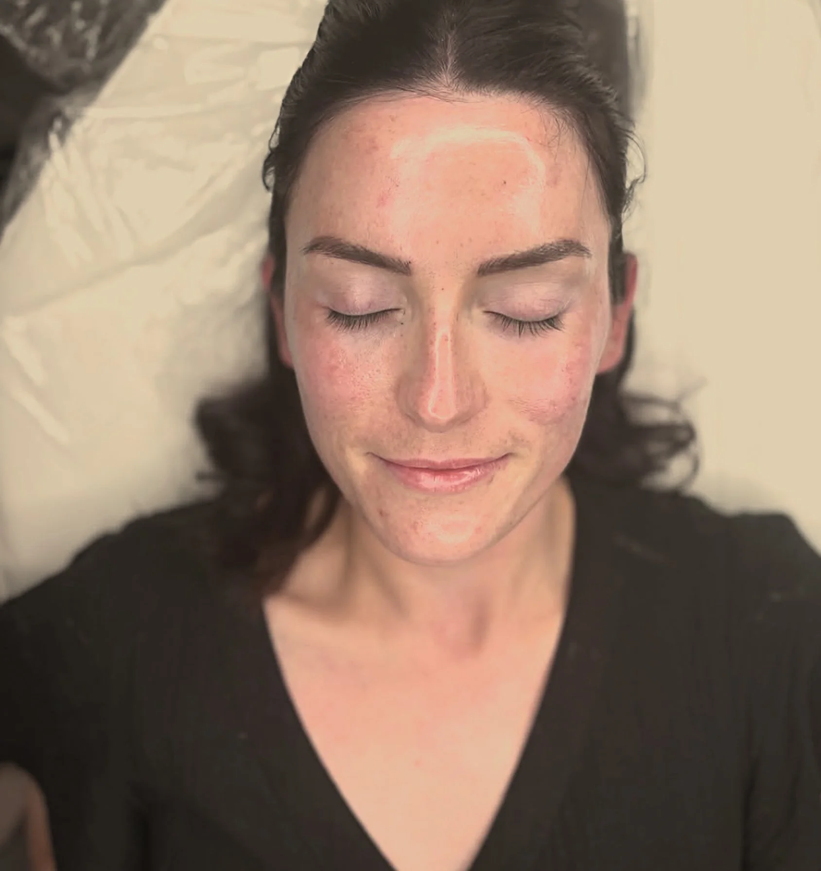 Close-up of a woman lying on her back with her eyes closed, showing her forehead, eyebrows, and upper cheeks.