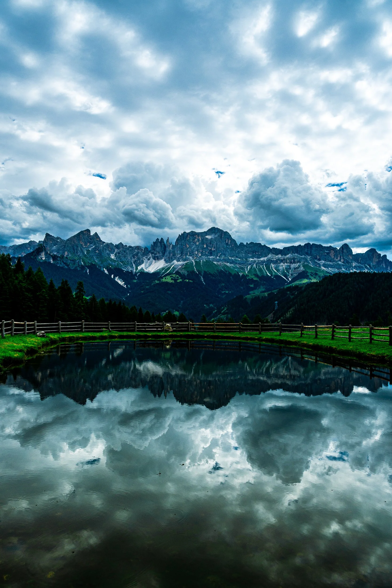 Mountain range reflected in a calm alpine lake beneath dramatic clouds