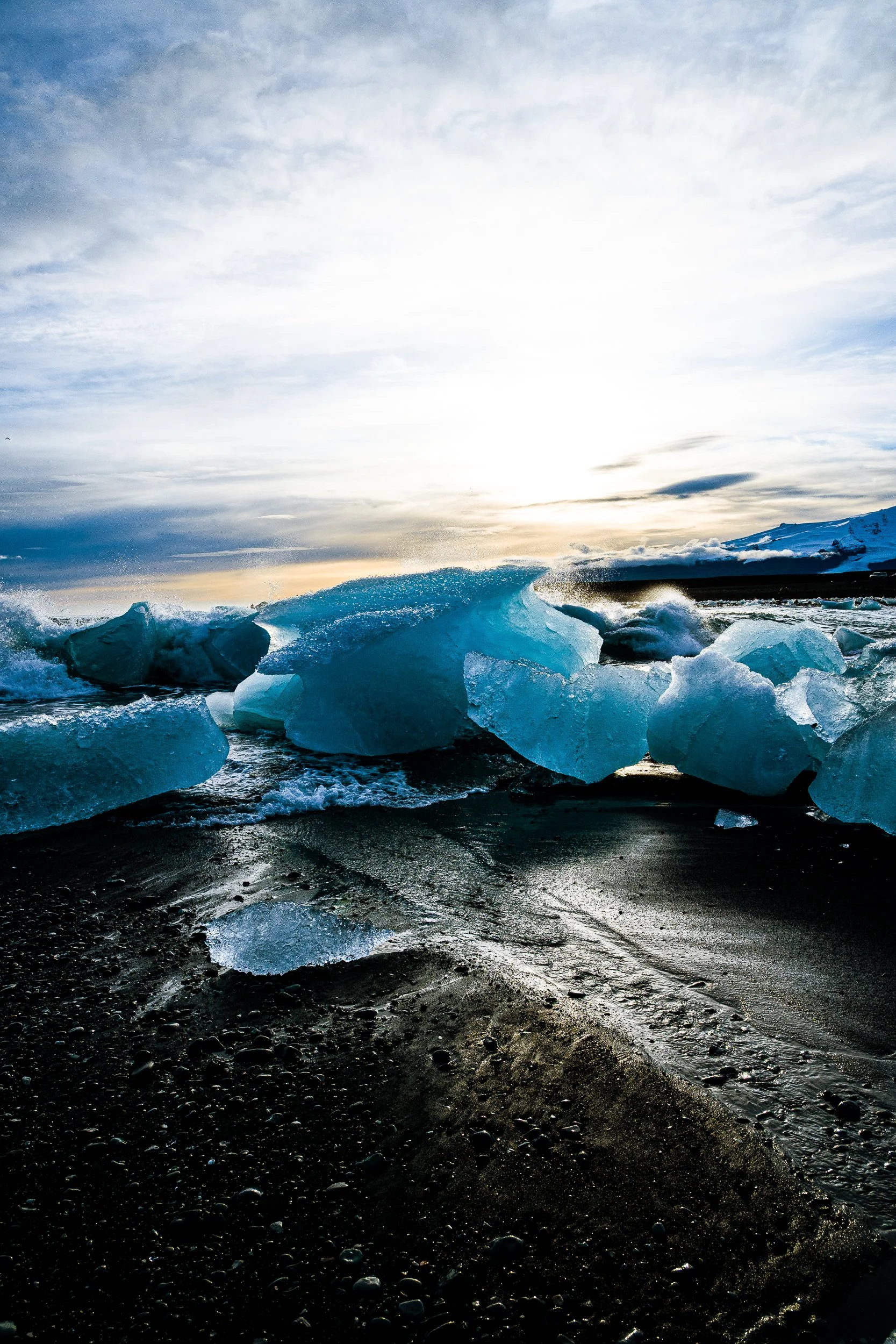 Blue icebergs scattered along Iceland’s black sand beach at sunset