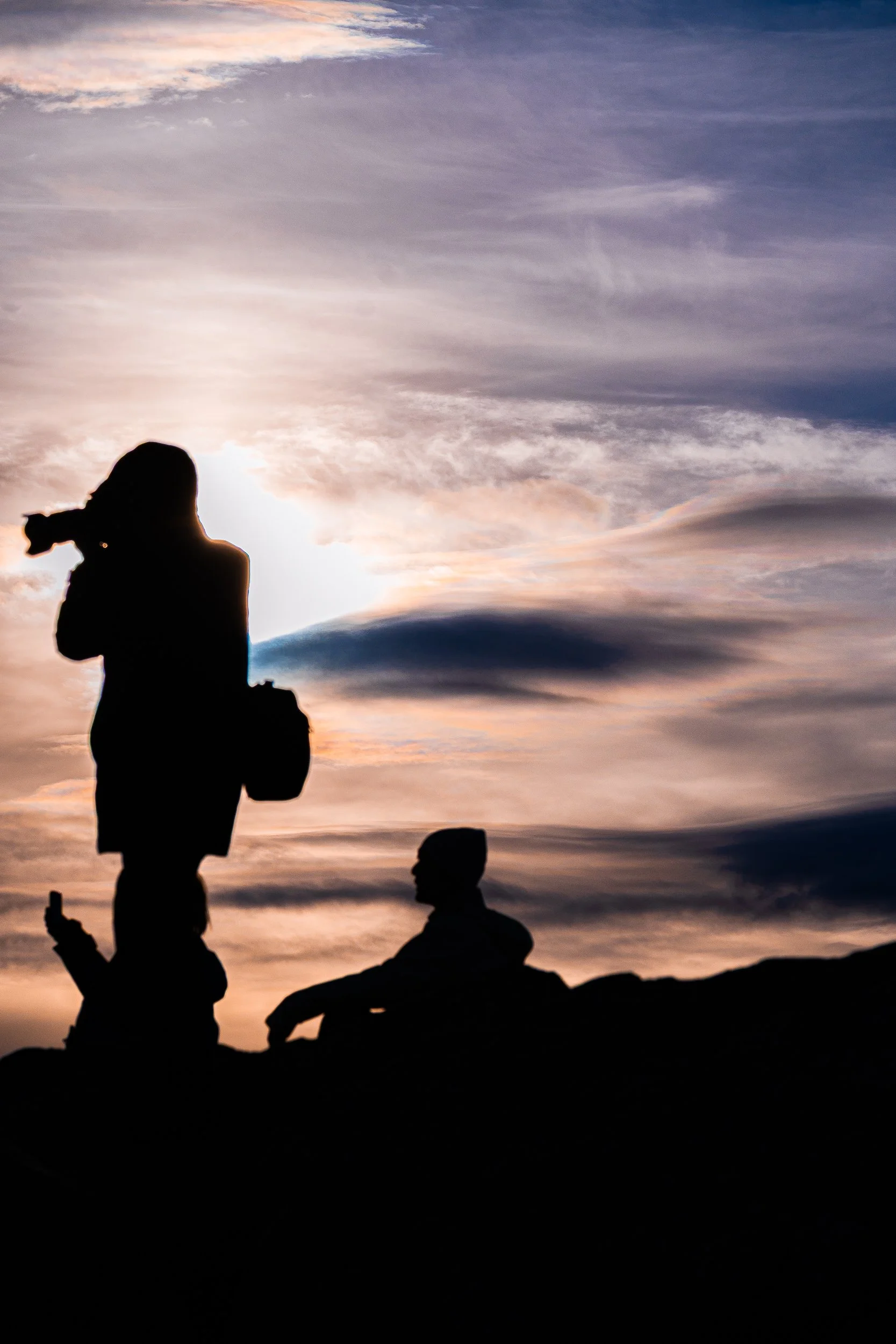 Silhouettes of two people against a colorful sunset sky with dramatic clouds