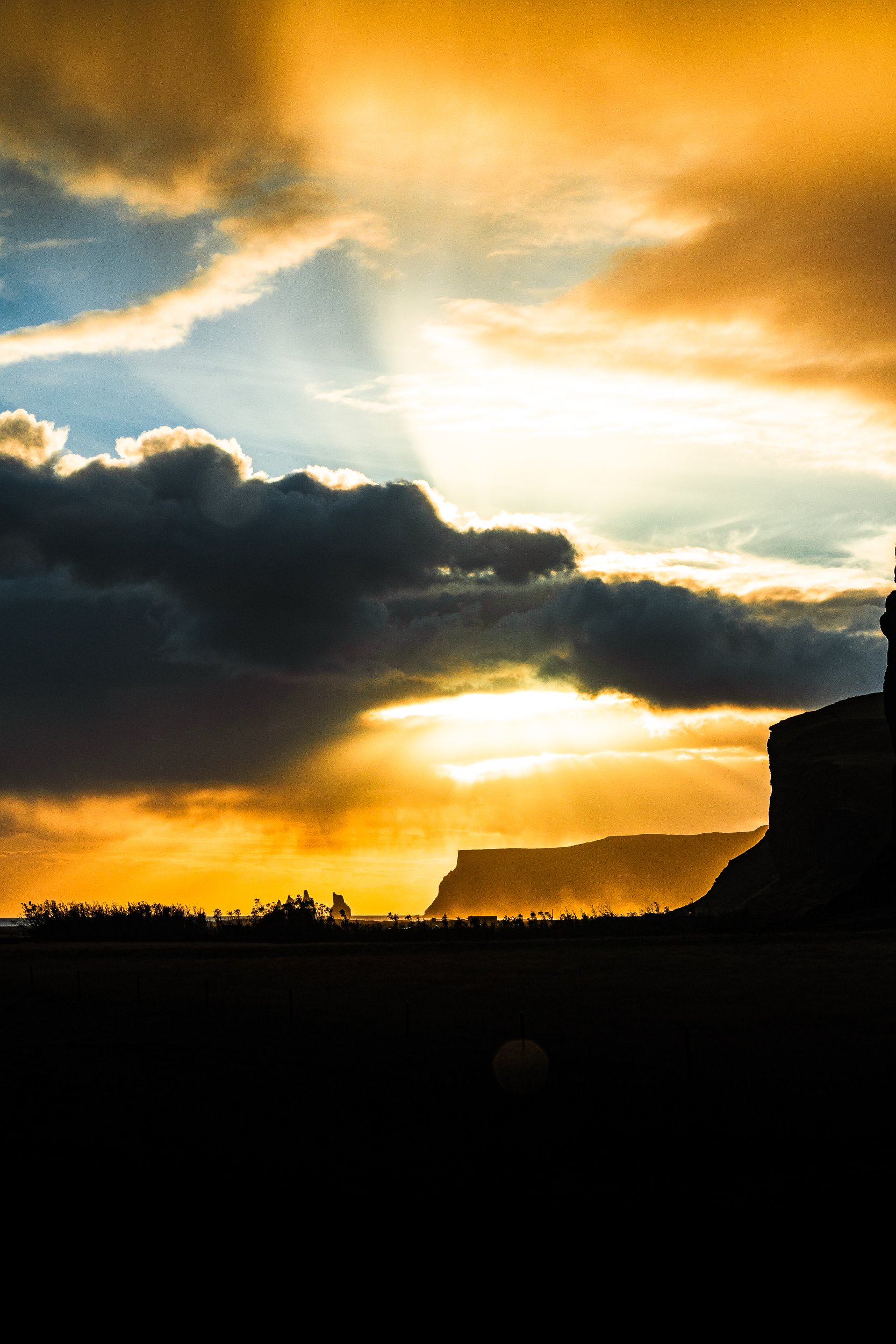 Golden sunset over dramatic clouds and silhouetted rocky cliffs