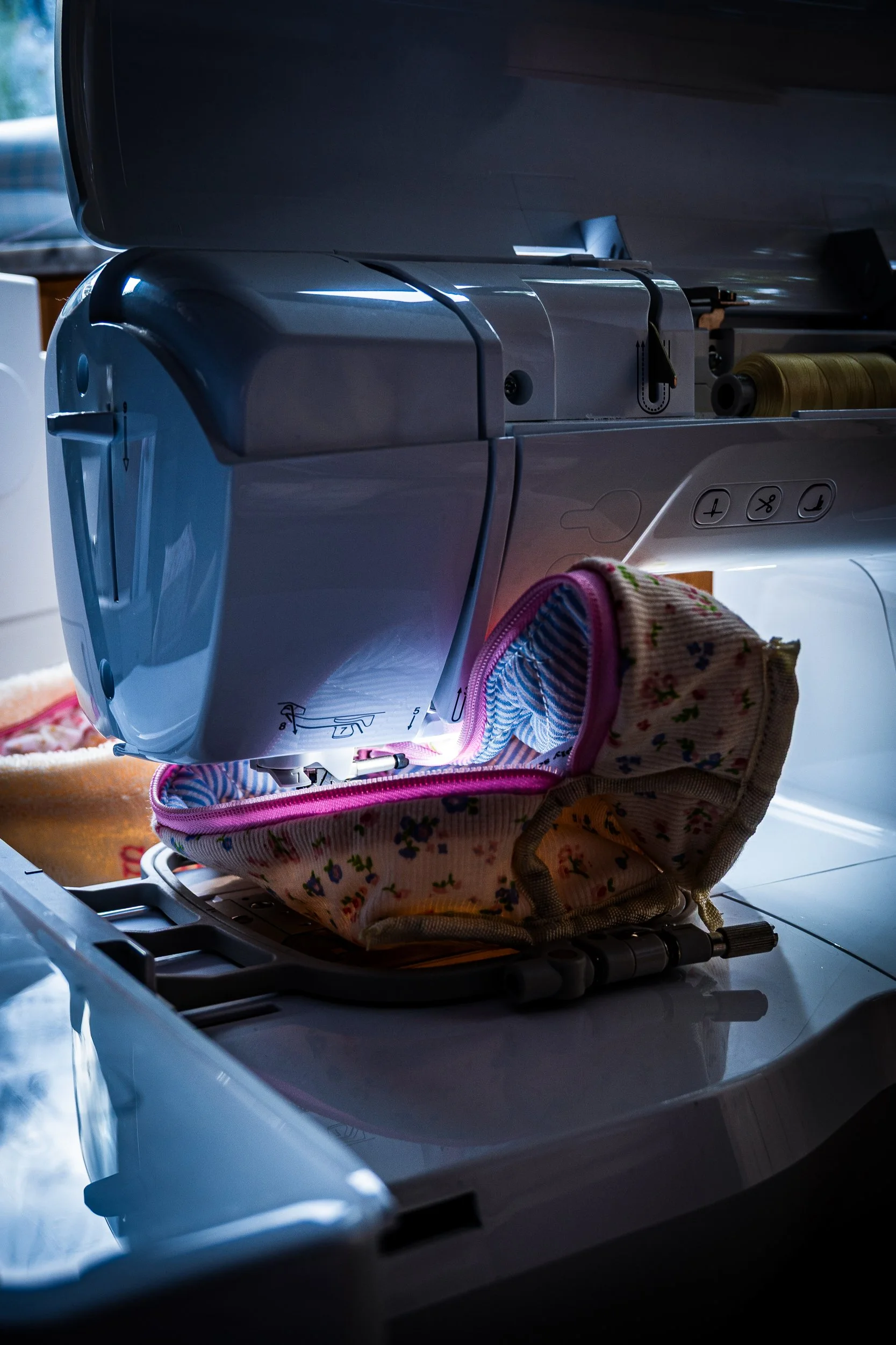 Close-up of a sewing machine stitching colorful fabric in an open floral sewing basket